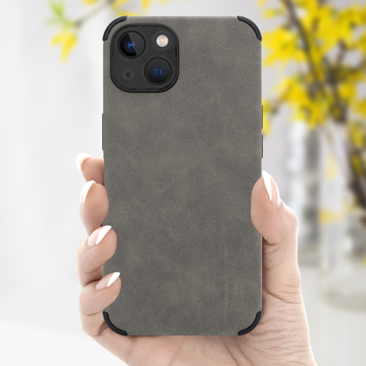 Hand hält graue Handyhülle mit schwarzen Ecken, Telefon und verschwommenem Hintergrund mit gelben Blumen.