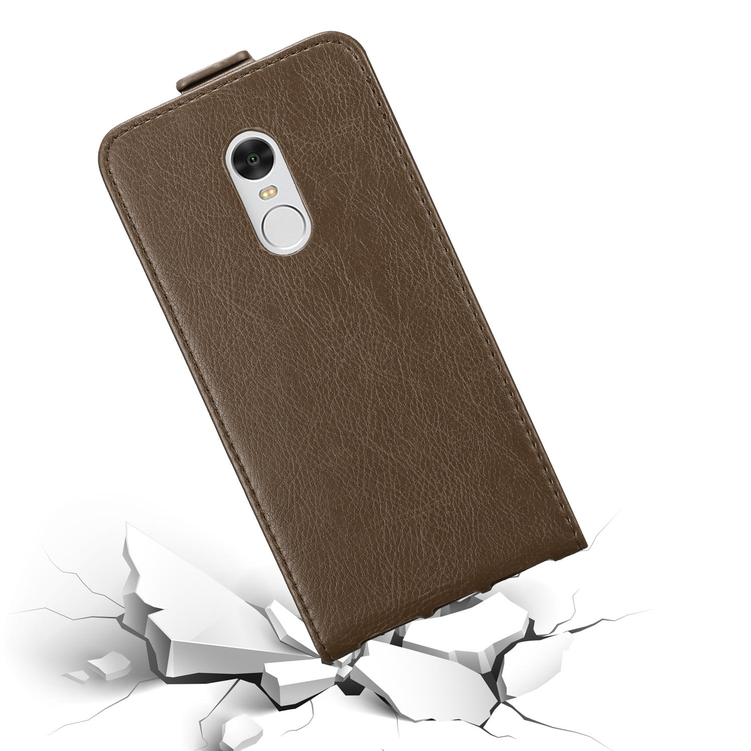 Custodia per telefono marrone, chiusa, con telefono all'interno, su superficie bianca con crepe.