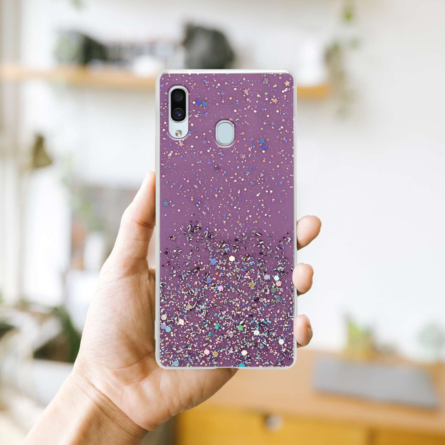 Hand hält eine lila Handyhülle. Hülle hat Glitzer-Design, zeigt Funkel-Effekt.