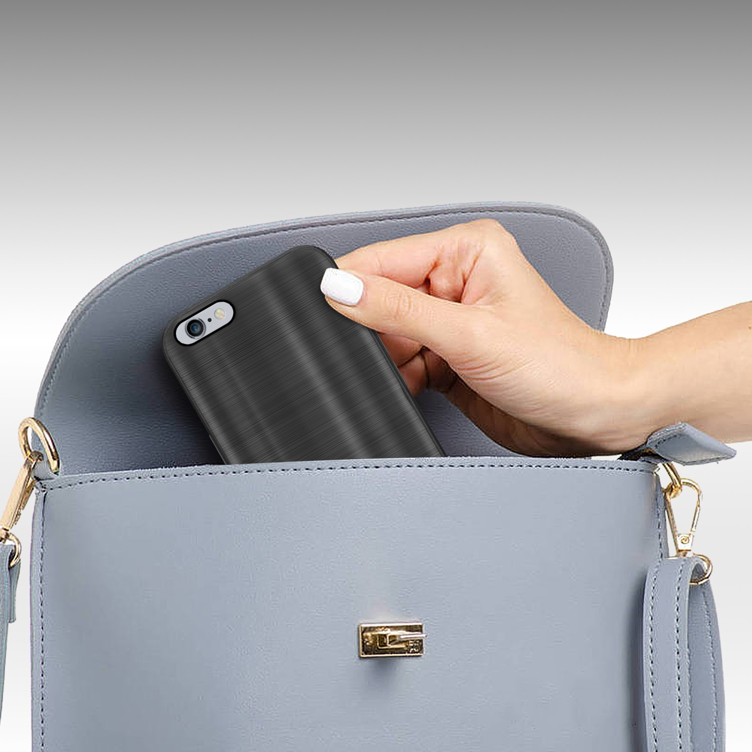 Eine Hand legt eine Handyhülle in eine graue Handtasche. Die Handyhülle ist schwarz.
