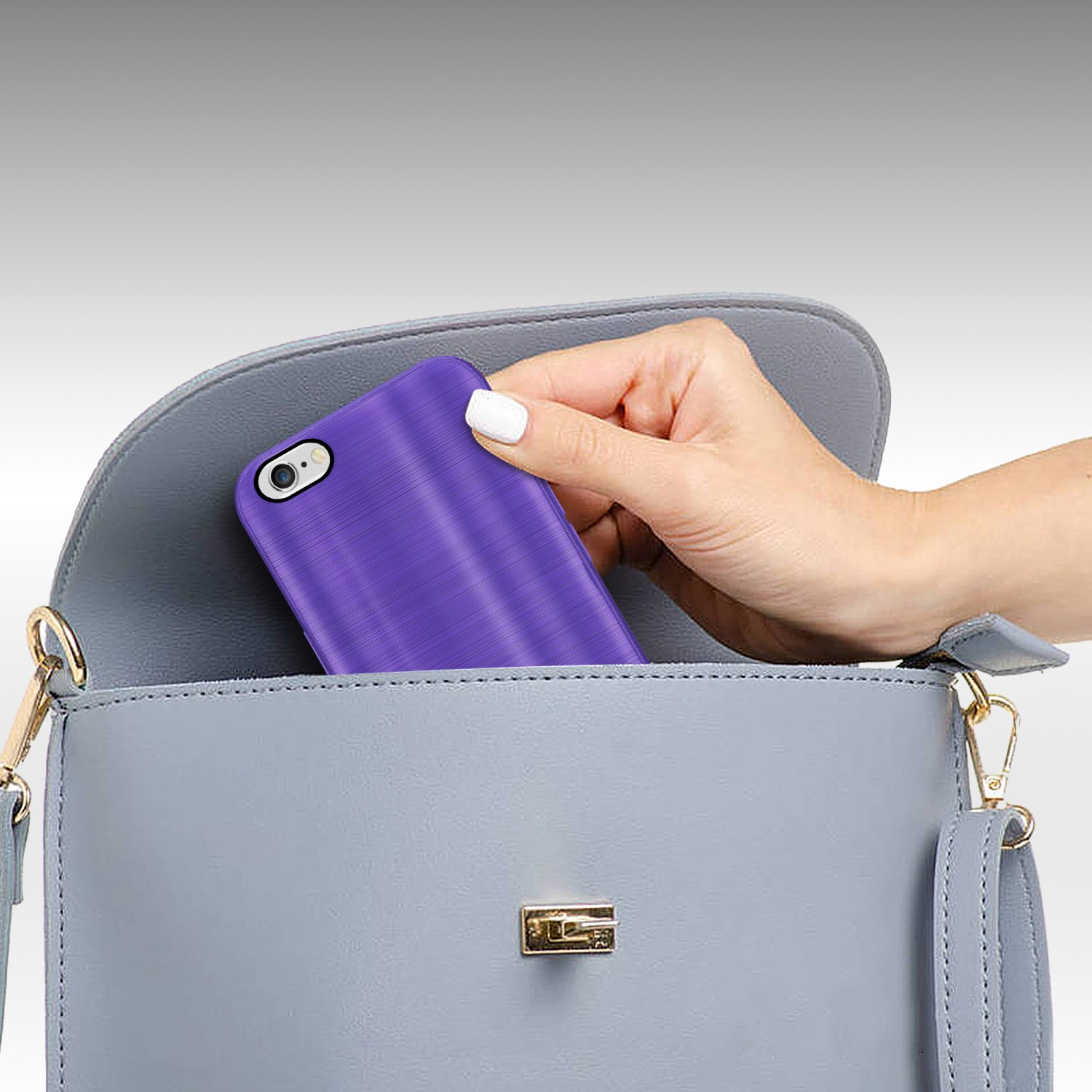 Hand legt ein lila Telefon in eine graue Handtasche. Die Handyhülle ist lila mit strukturierter Oberfläche.