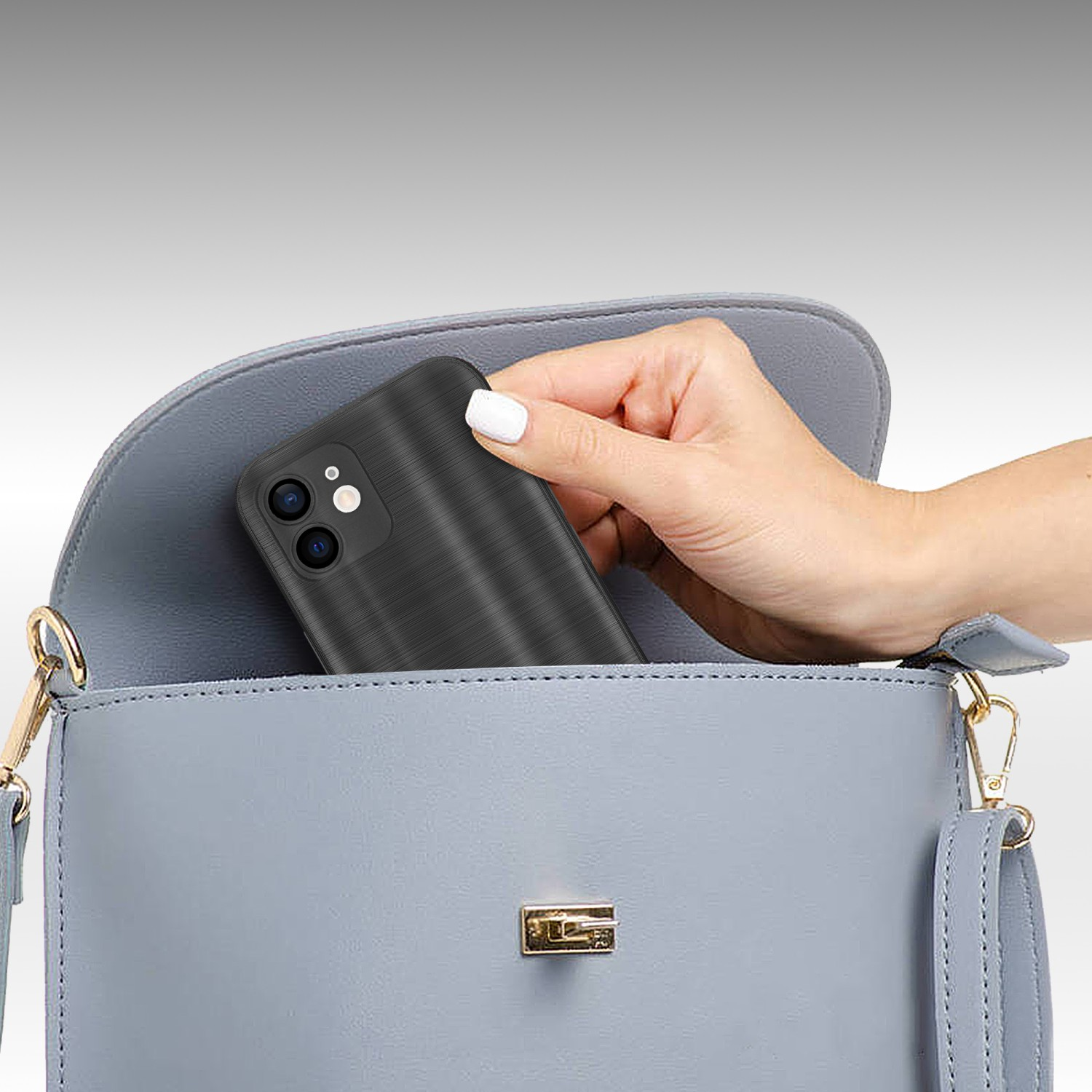 Una mano che mette un telefono cellulare nero in una borsetta azzurra. La borsa ha una catena d'oro.