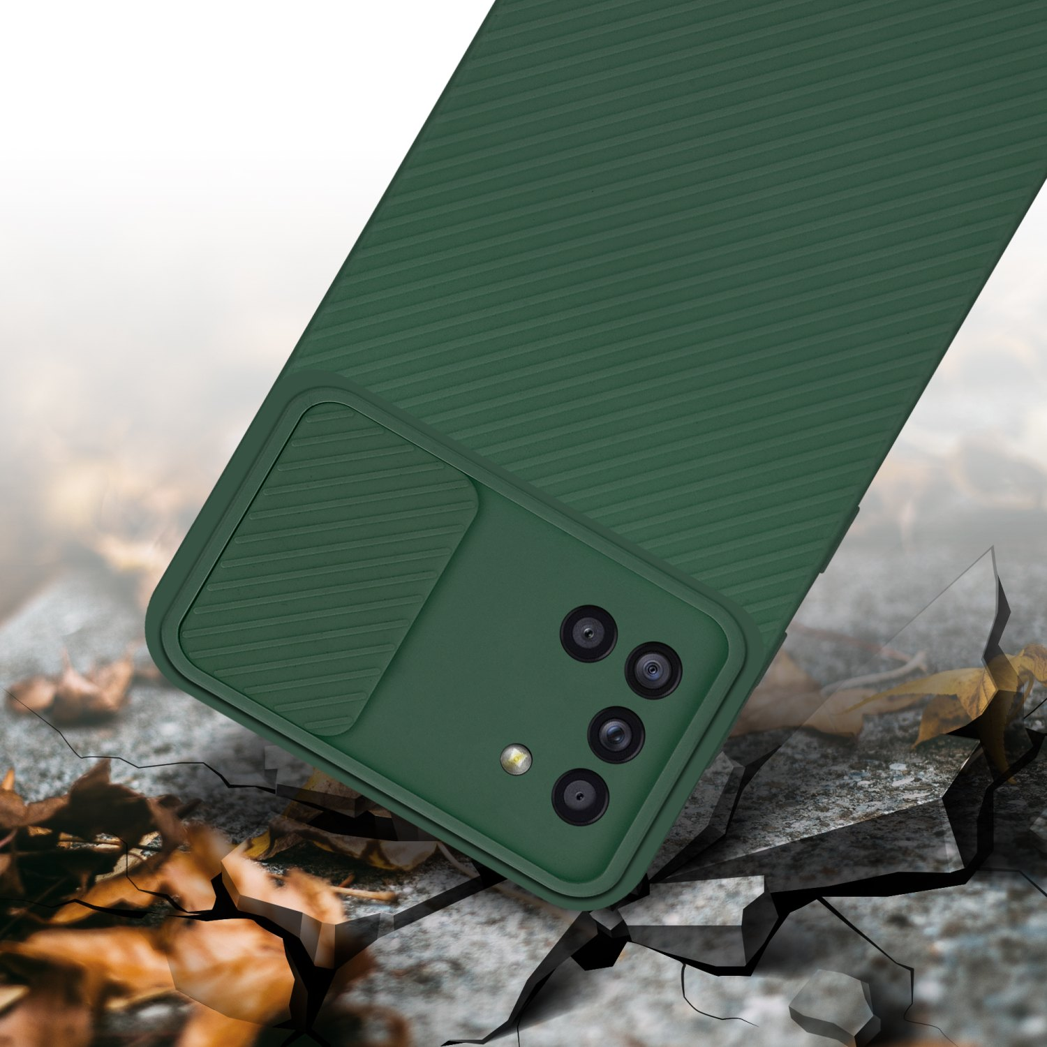 Grüne Handyhülle. Telefon darin. Boden mit Rissen und Blättern, unscharfer Hintergrund.
