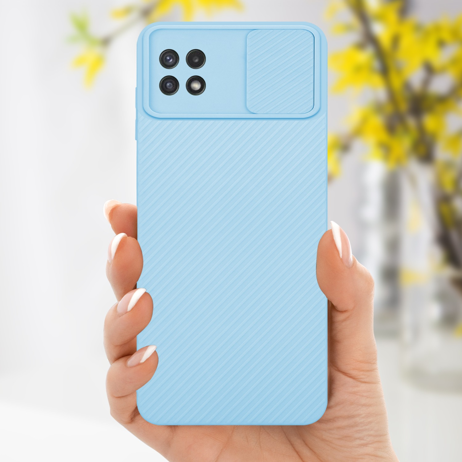 Hellblaue Handyhülle mit Kameraabdeckung. Hand hält das Telefon. Gelbe Blumen.