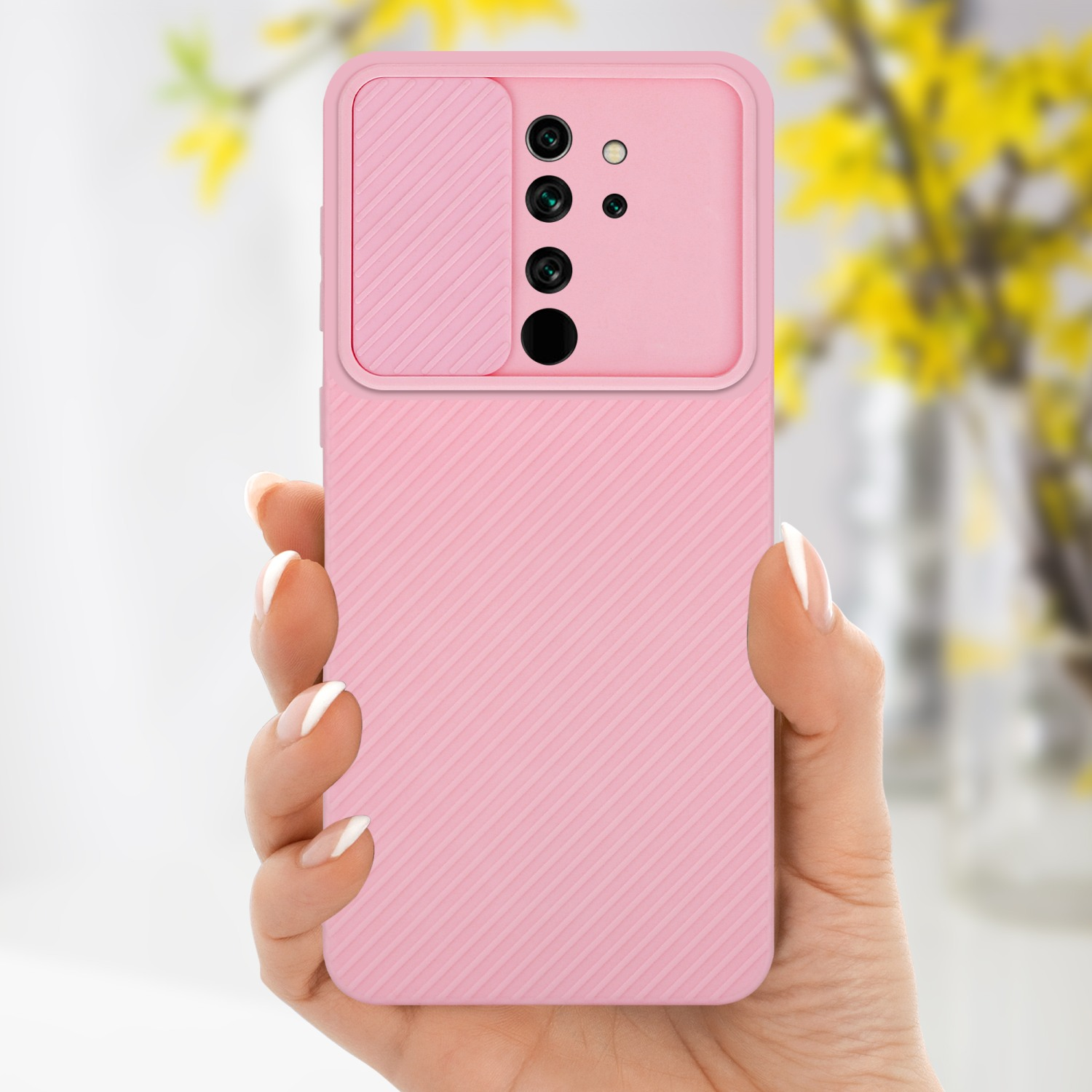 Custodia rosa per telefono, tenuta in mano. Fiori gialli sfocati sullo sfondo.