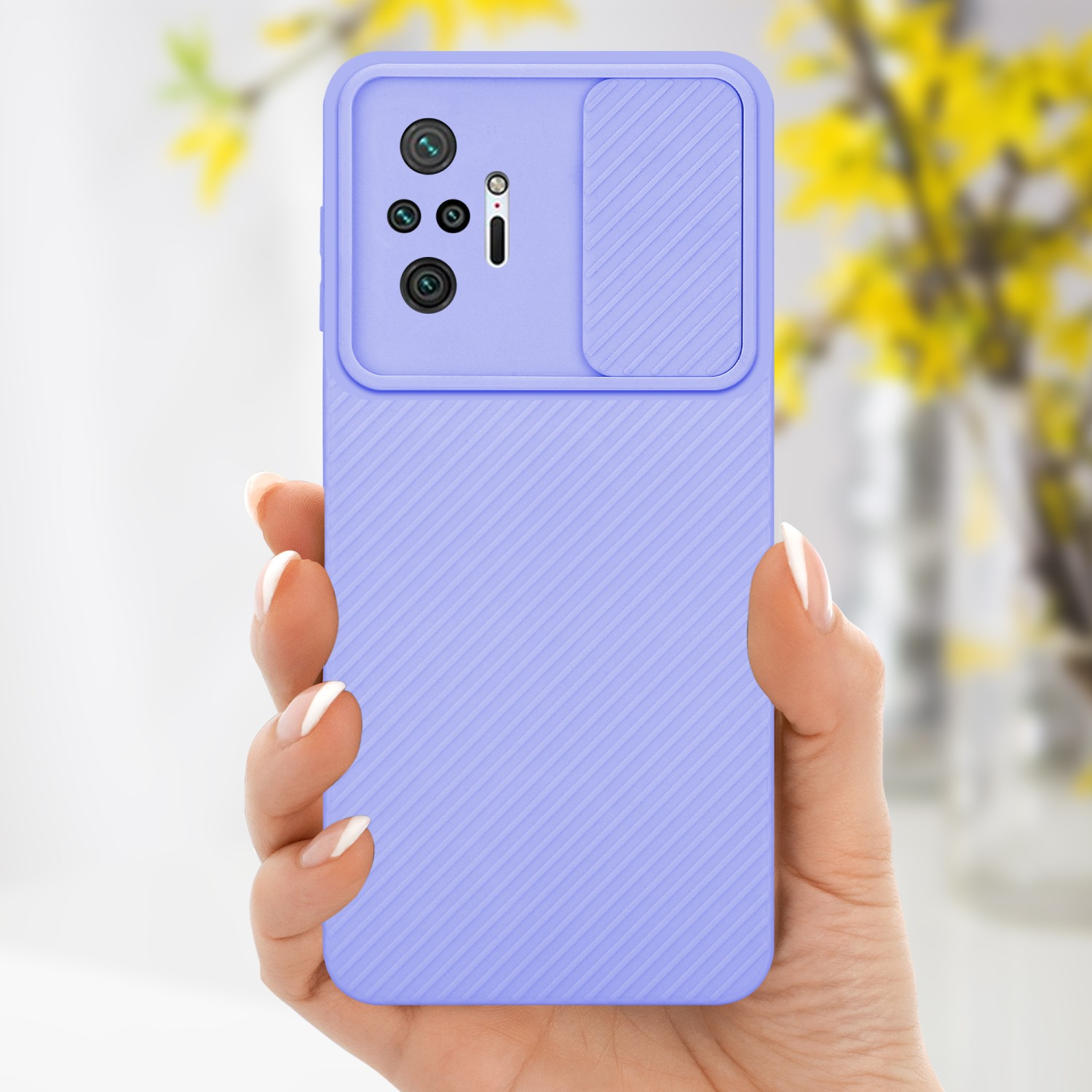 Una mano che tiene una custodia viola per telefono con una copertura per la fotocamera. Fiori gialli sullo sfondo.