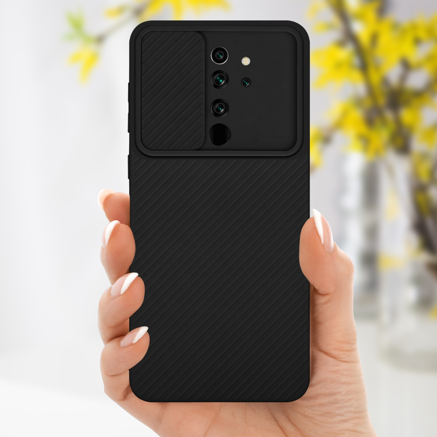 Custodia per telefono nera con copertura della fotocamera tenuta in mano. Fiori gialli sullo sfondo.