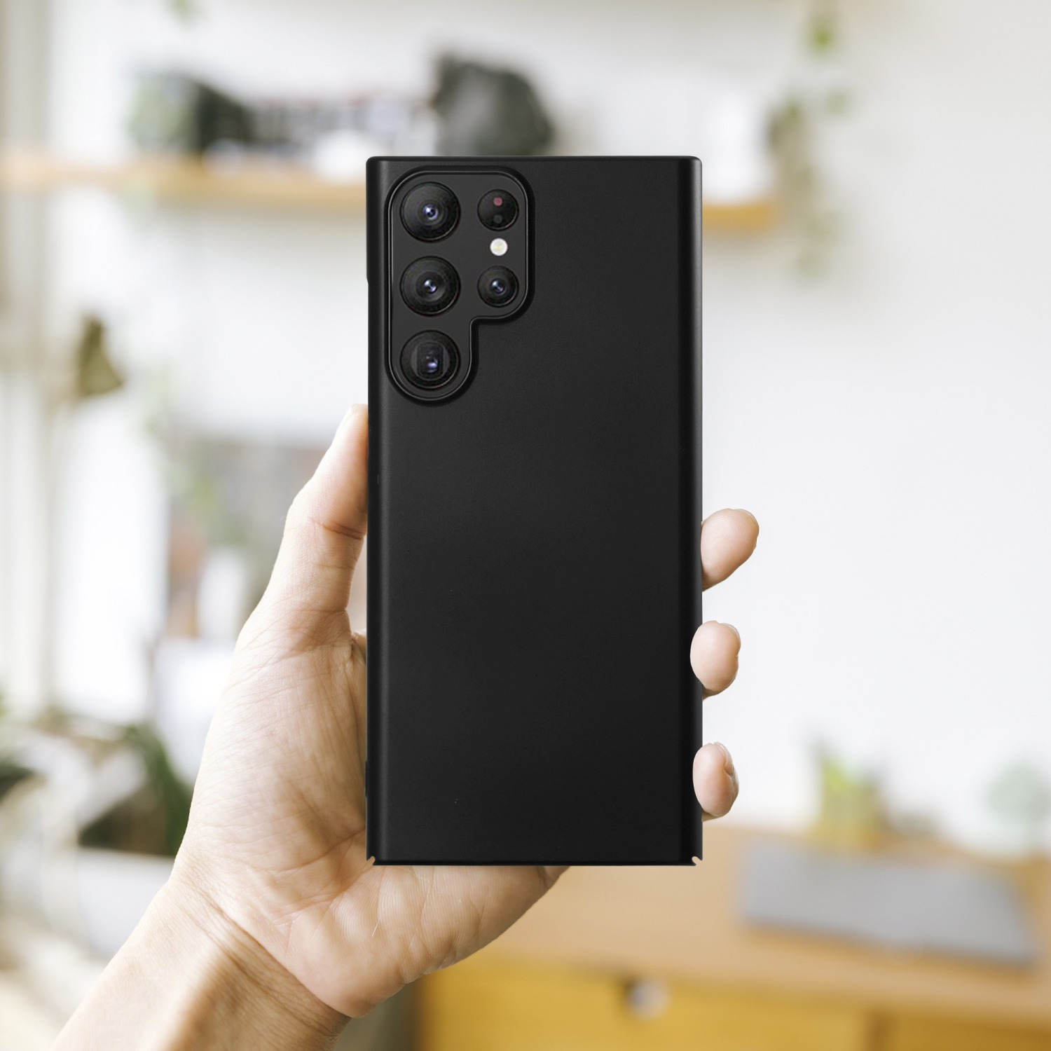 Hand hält ein schwarzes Smartphone. Mehrere Kameralinsen sind sichtbar.