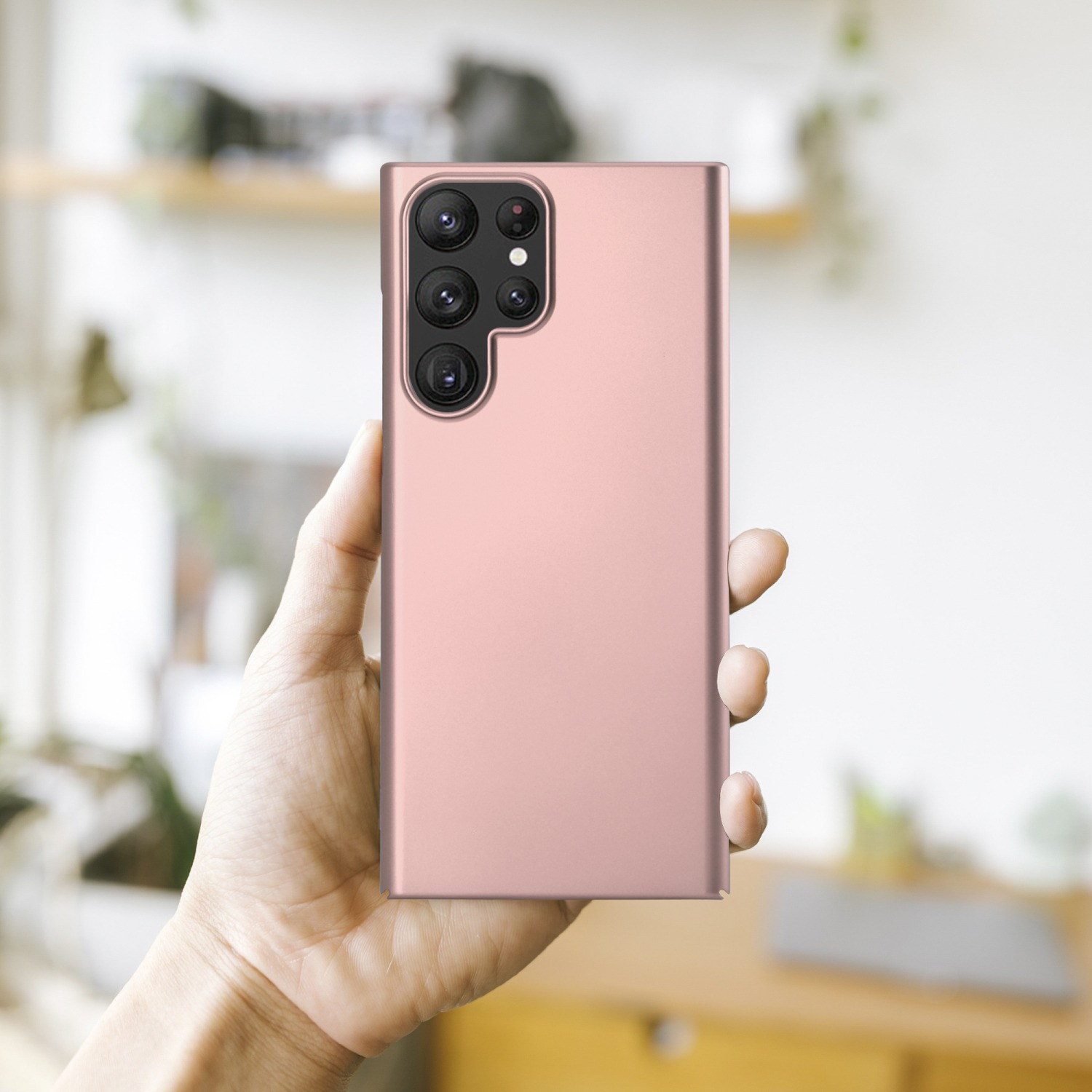 Eine Person hält ein roségoldenes Telefon. Das Telefon hat die Kameralinsen auf der Rückseite.