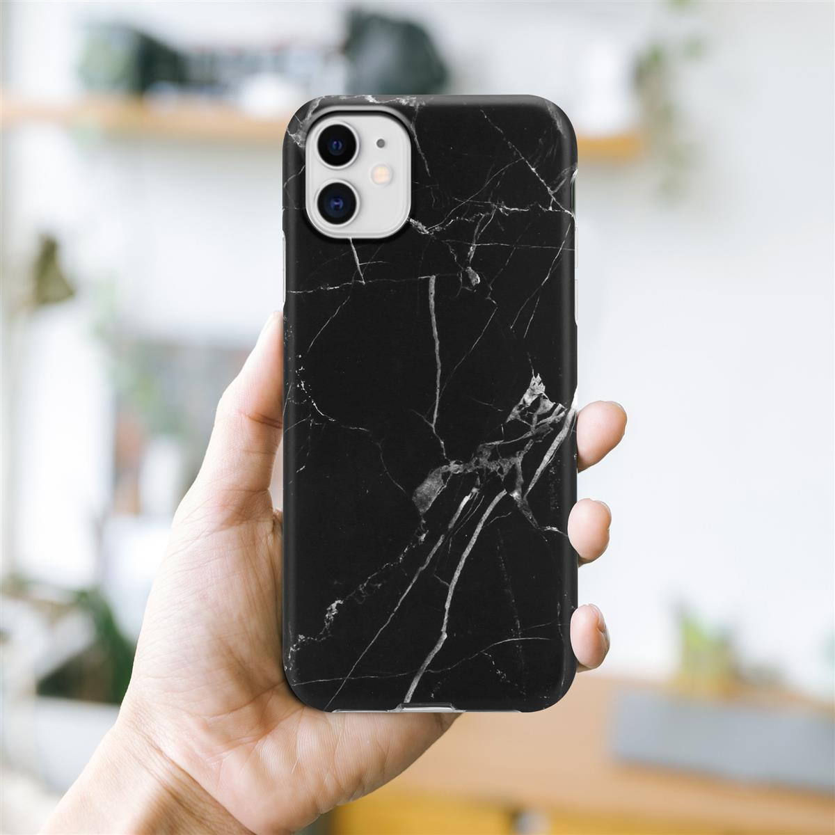 Una mano che tiene un telefono in una custodia con motivo marmoreo nero, con sfondo sfocato.