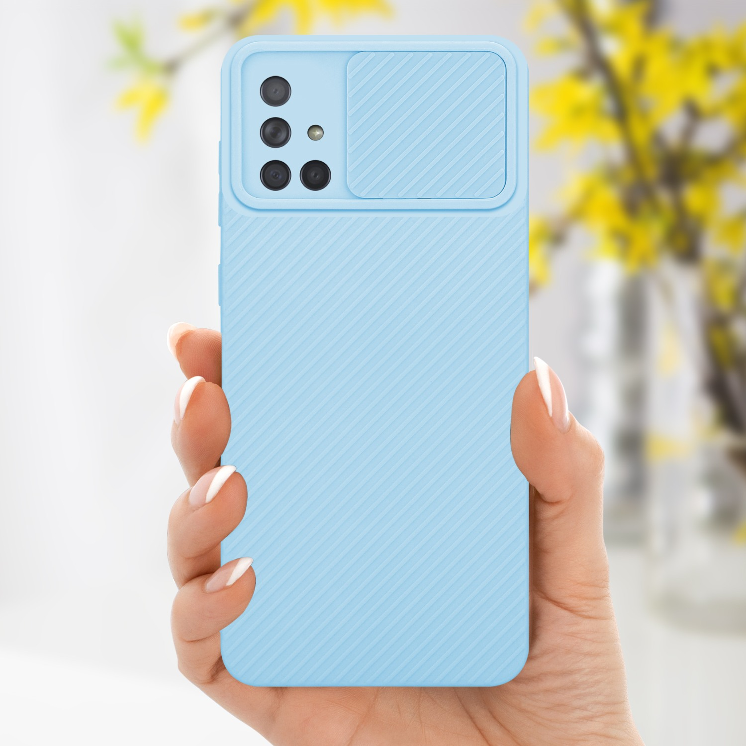 Hand hält hellblaue Handyhülle mit Kameraabdeckung und Blumen im Hintergrund.