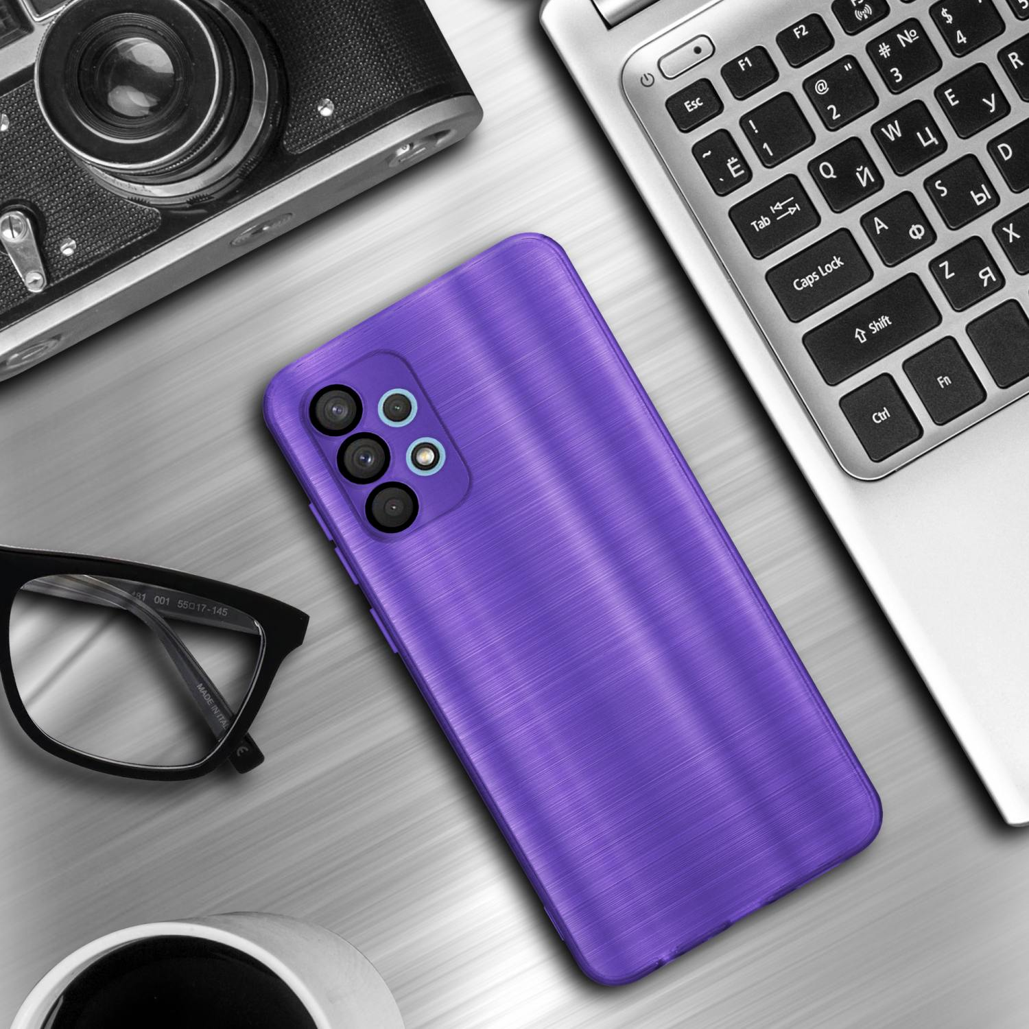 Una custodia viola su un tavolo con un laptop, occhiali e una fotocamera. La custodia è a fuoco.