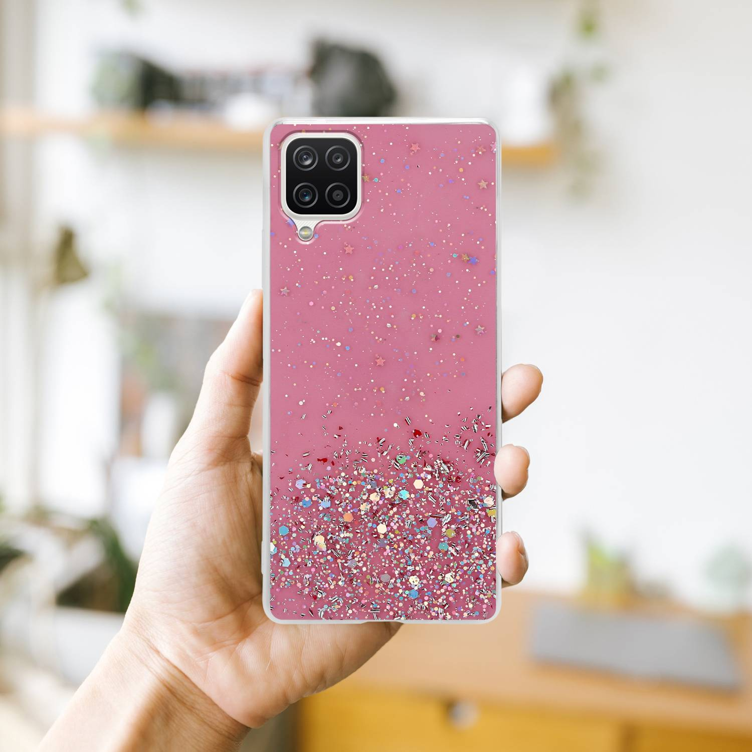 Hand hält eine rosa Handyhülle mit Glitzer. Die Hülle hat einen Kameraausschnitt.