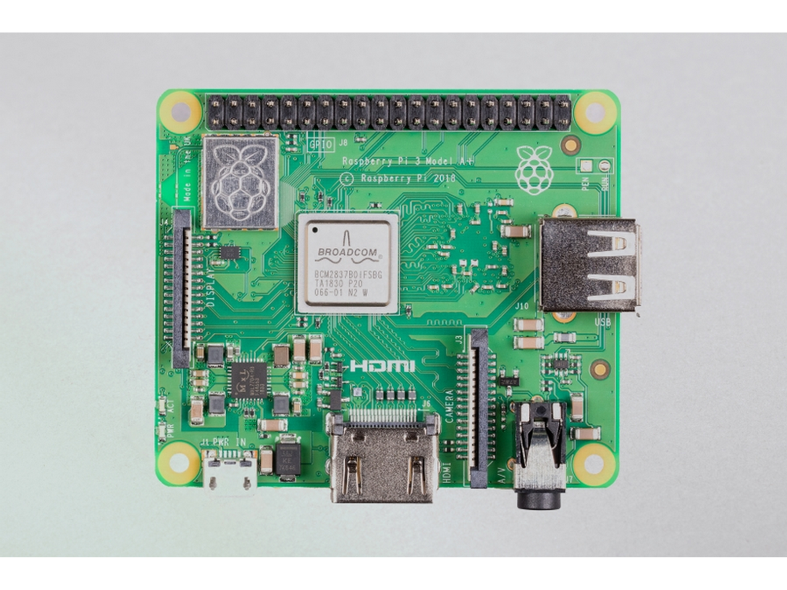 Placa de circuito verde de una Raspberry Pi 3 Model A+, con componentes y conectores visibles. Fondo blanco.