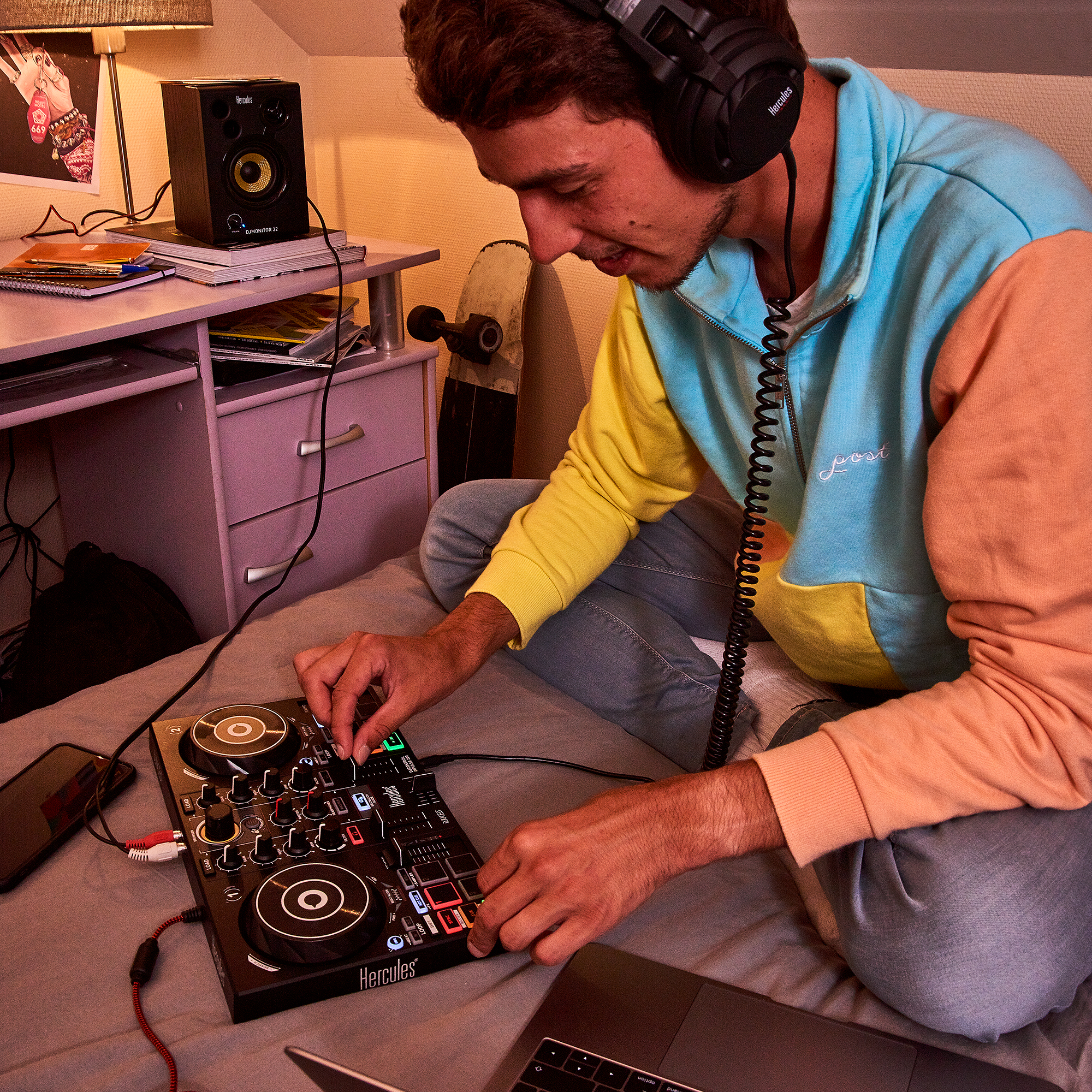 Hombre con auriculares y equipo de DJ. Portátil y altavoz en el fondo.
