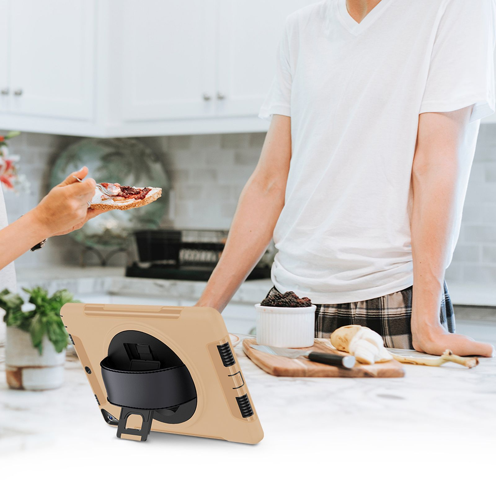 Zwei Personen interagieren in einer Küche mit einem Tablet. Eine Person hält ein Sandwich.