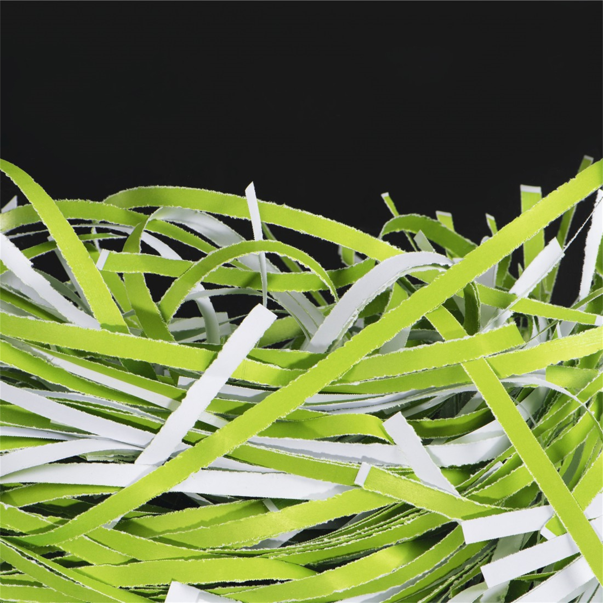 Pocięty papier, zielony i biały, wypełniający ramkę na czarnym tle.