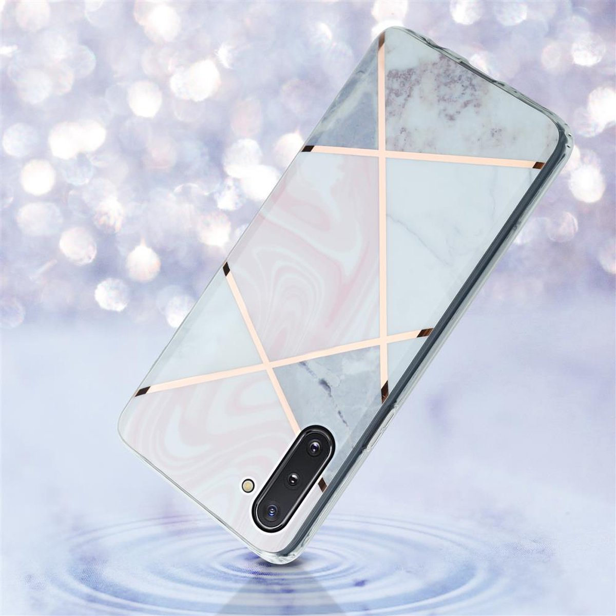 Custodia per telefono in marmo bianco e rosa con linee geometriche dorate, angolata su sfondo sfocato e luminoso.