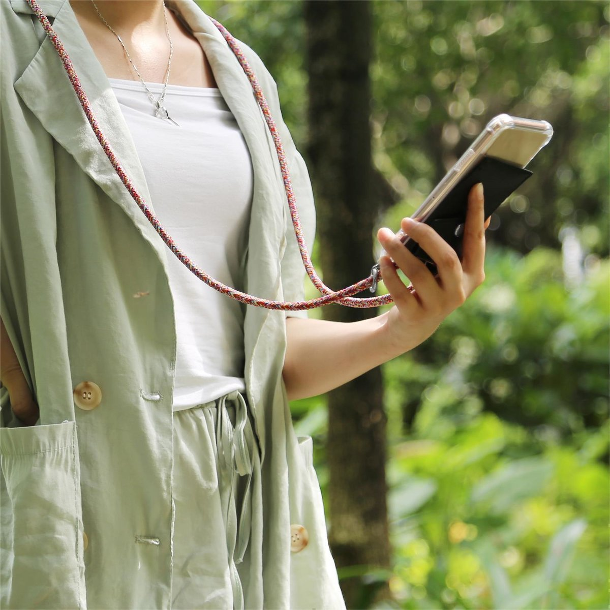 Eine Person hält ein Telefon in schwarzer Hülle mit rotem und weißem Umhängeband.