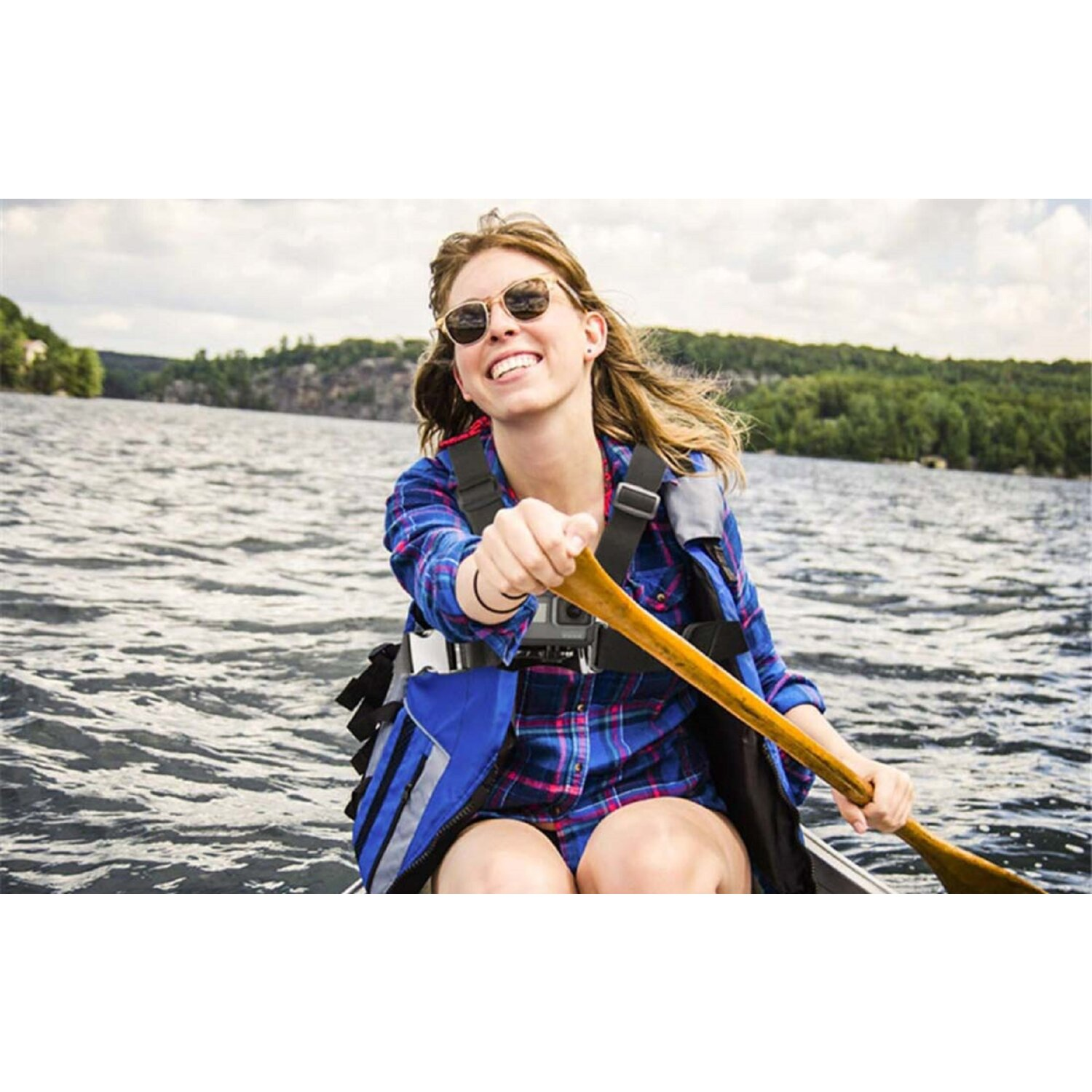 Eine Frau in einem Kanu auf dem Wasser. Sie lächelt und trägt eine Sonnenbrille. Sie hält ein Paddel.