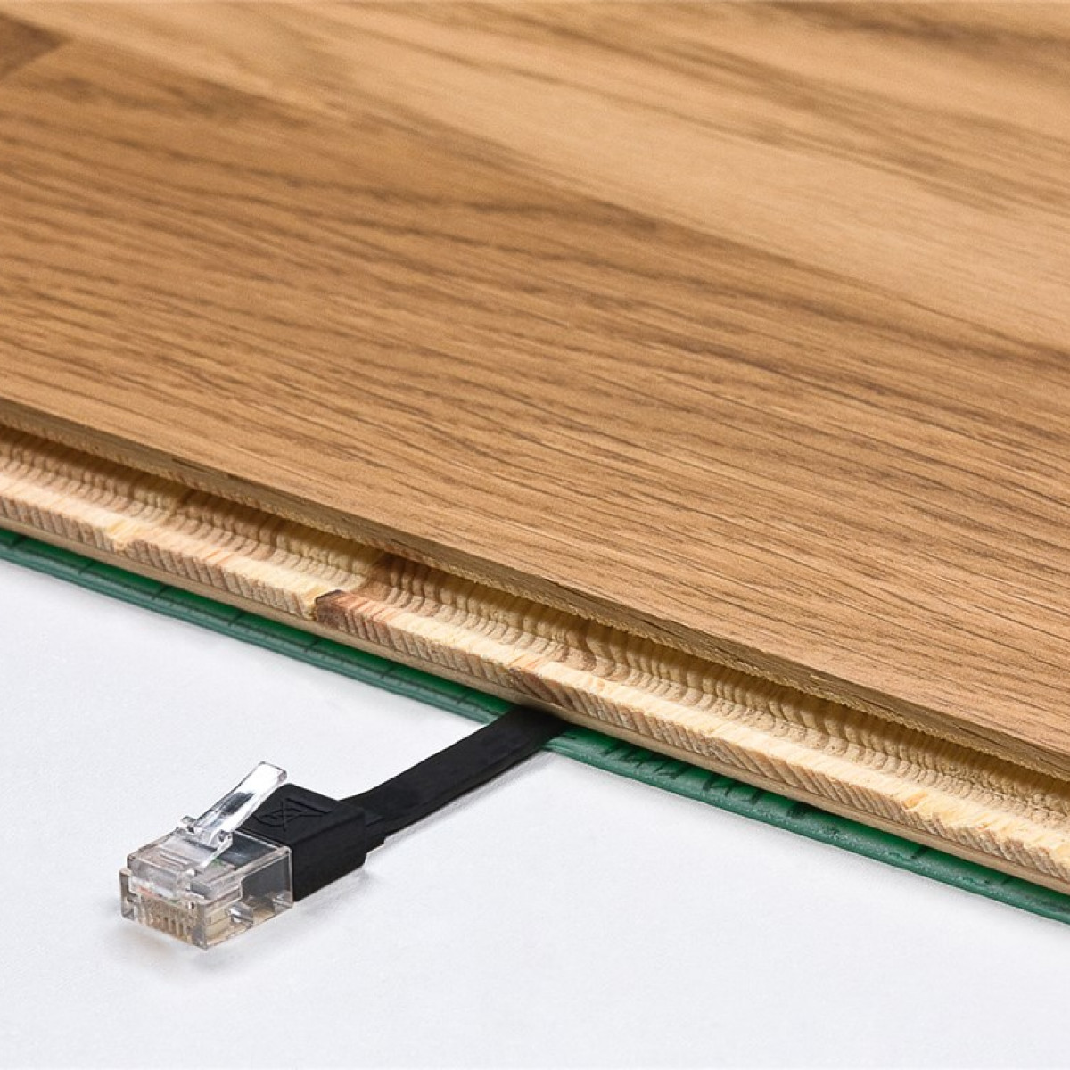 Close-up van een netwerkkabel met een transparante connector die in een houten vloer is gestoken.
