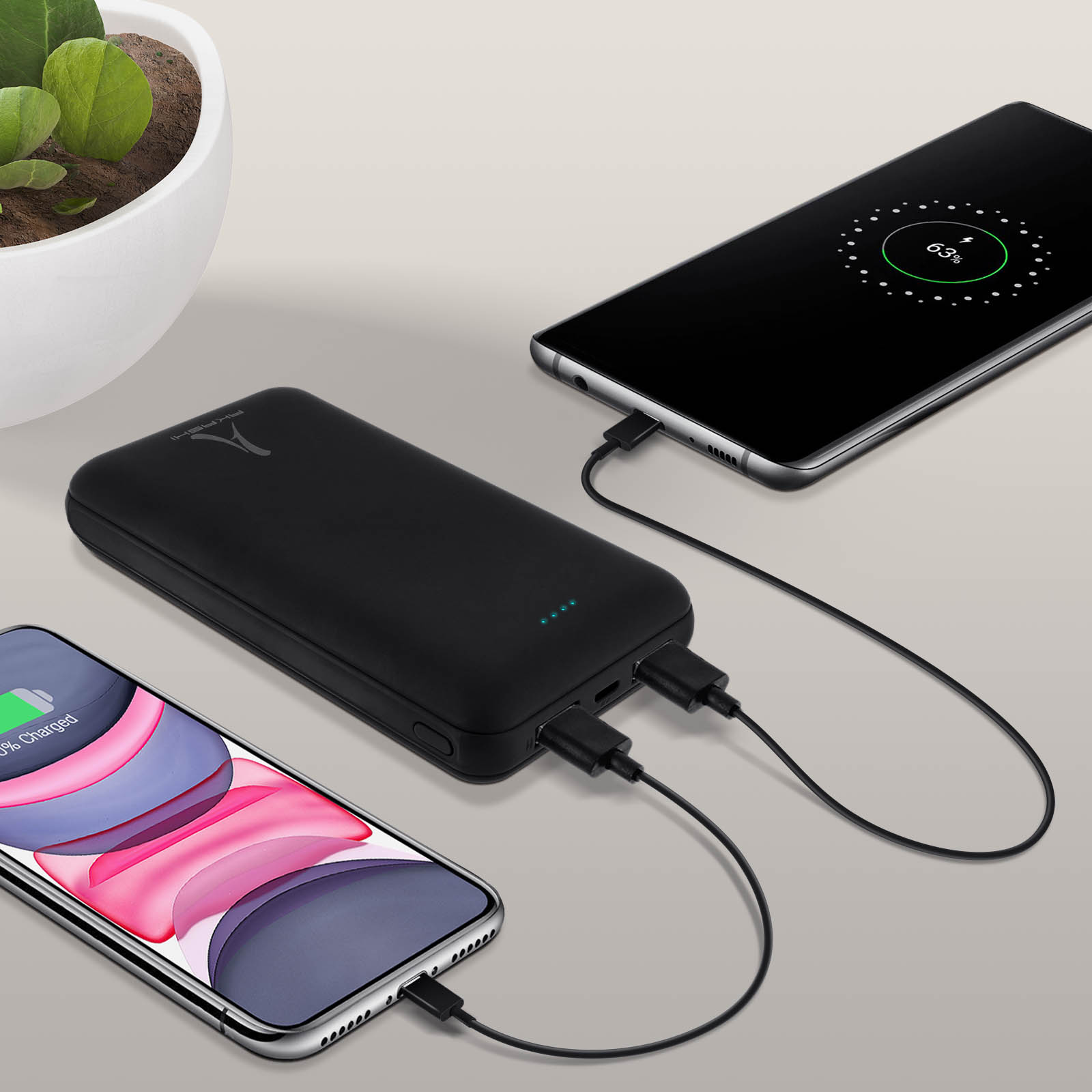Zwei Telefone laden von einer schwarzen Powerbank. Ein Telefon zeigt 65% geladen.