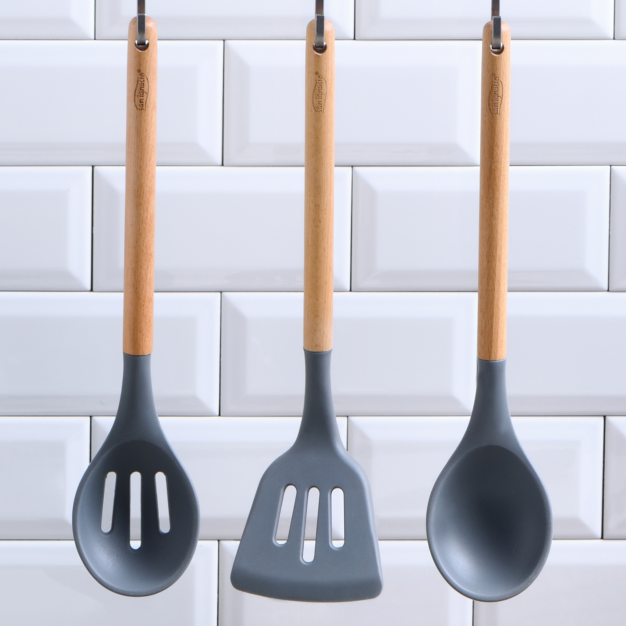 Tres utensilios de cocina con mangos de madera y cabezas de silicona grises.