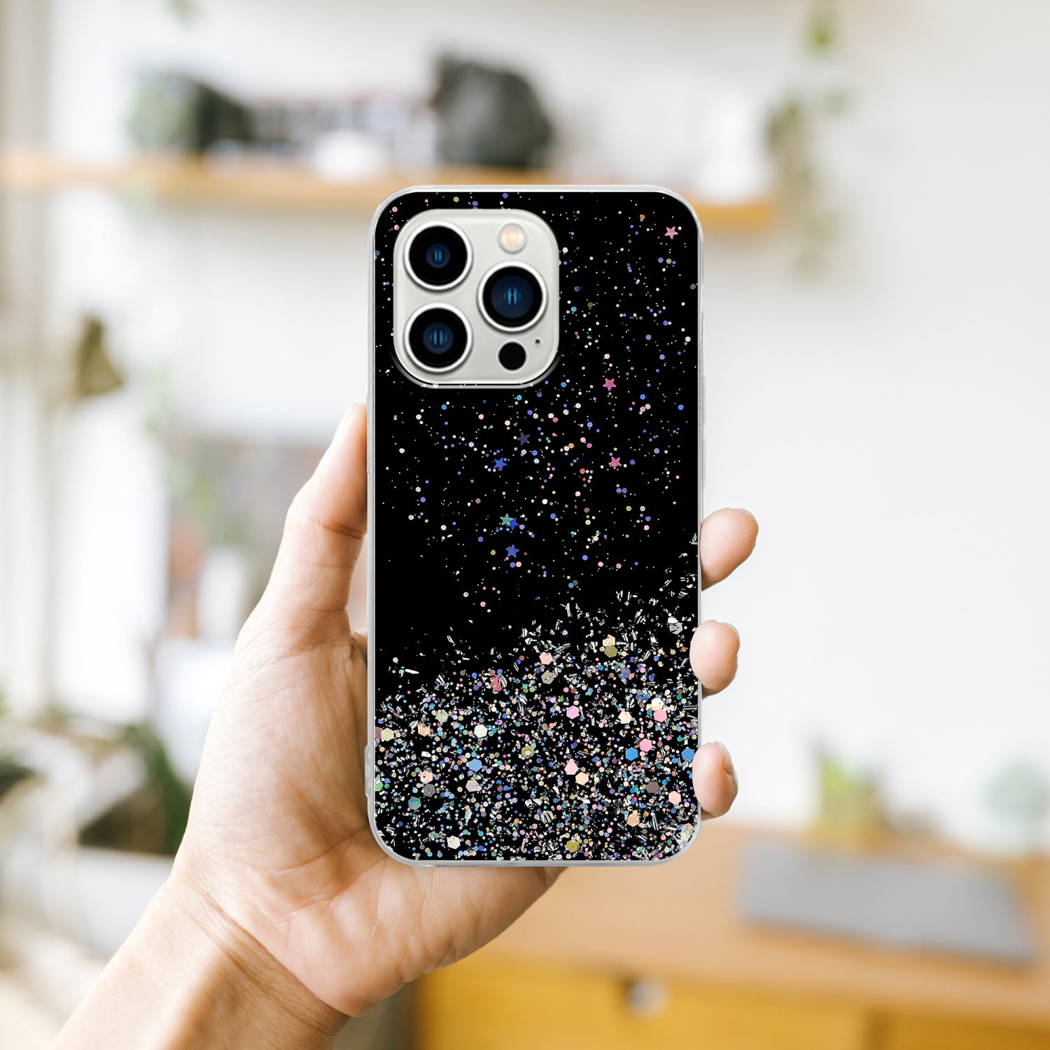 Hand hält Telefon mit schwarzer Hülle, bedeckt mit bunten Glitzer.