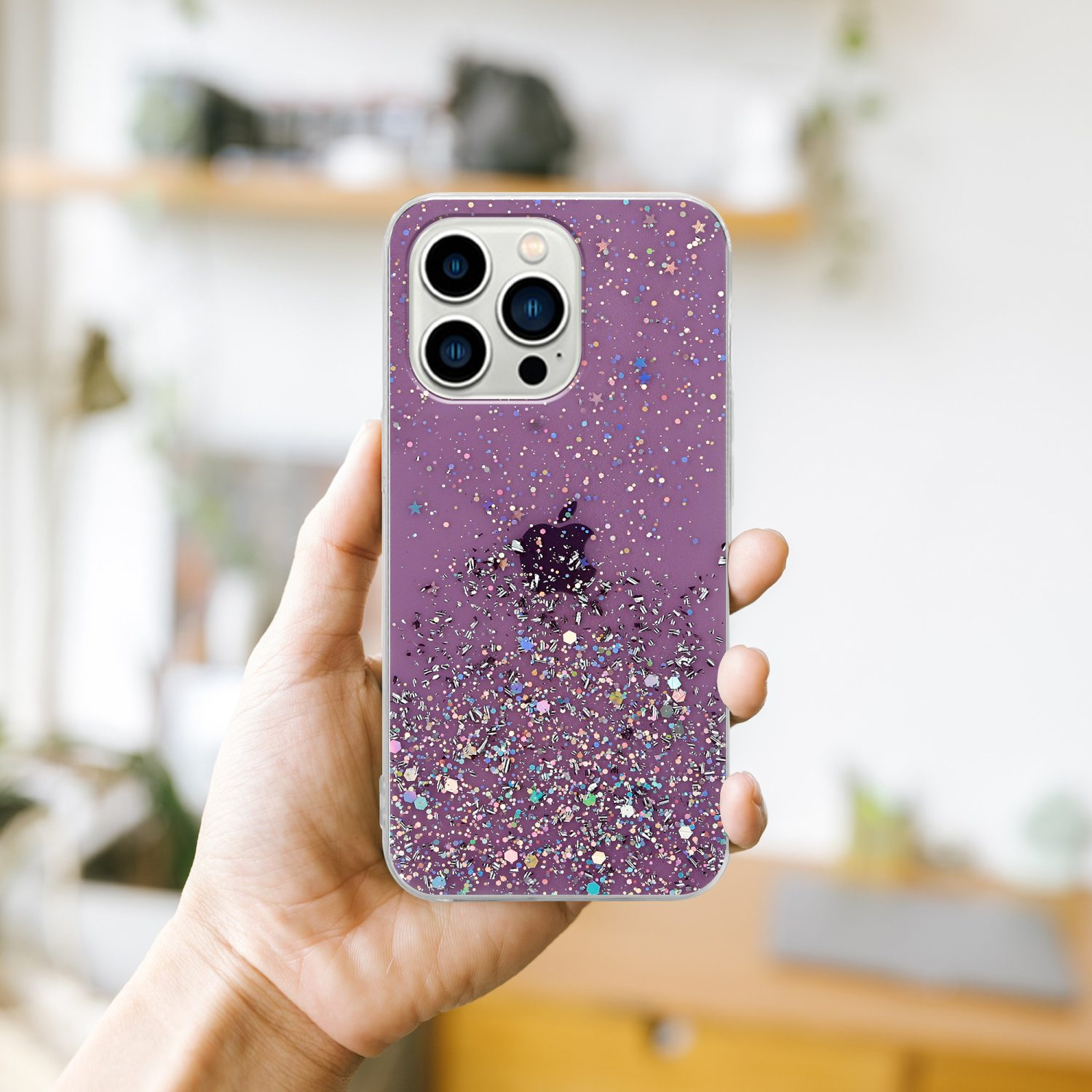 Lila Handyhülle mit Glitzerdesign, in der Hand gehalten, mit unscharfem Hintergrund.