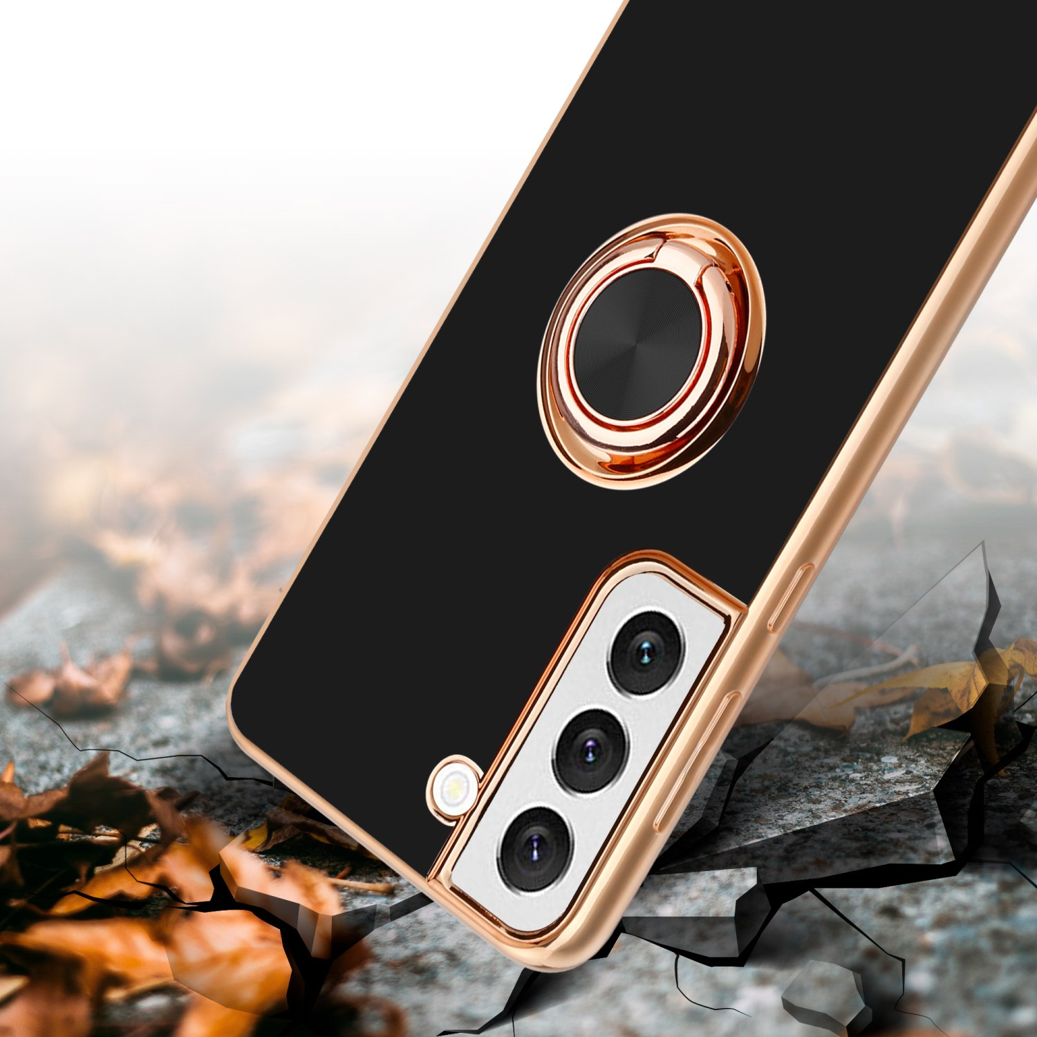 Custodia per telefono nera con anello di supporto dorato, su una superficie crepata. Focus sull'anello e sulla fotocamera.