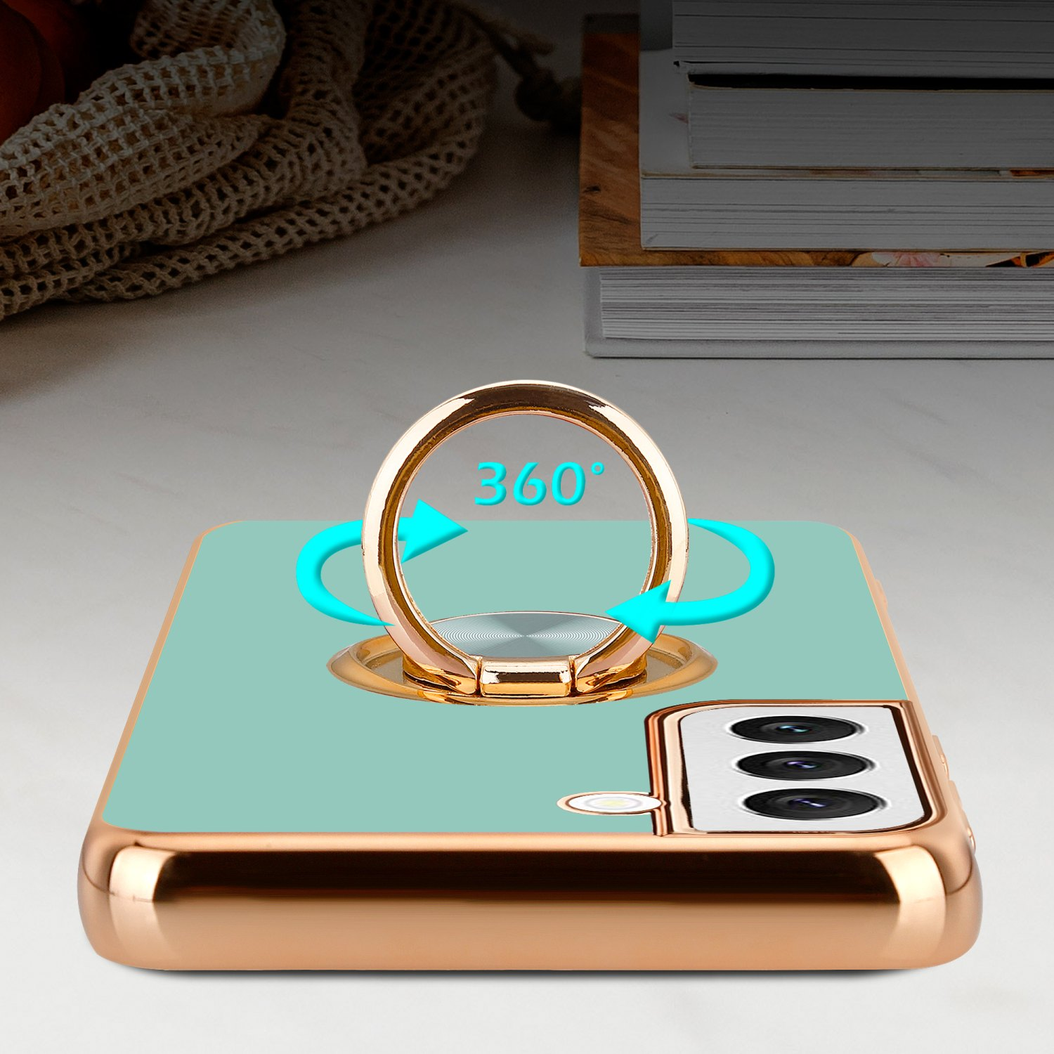 Telefono con supporto ad anello su custodia dorata, sfondo turchese, frecce 360°.