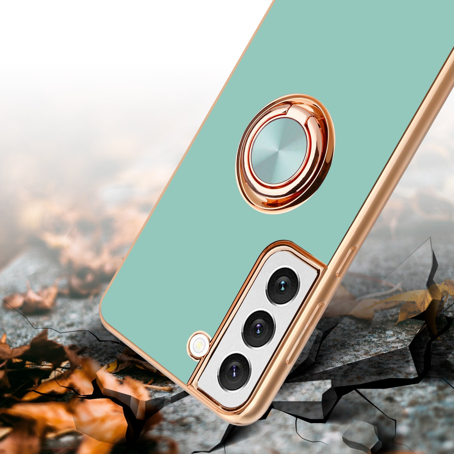Custodia per telefono verde menta con anello e dettagli dorati. La custodia è su una superficie incrinata.