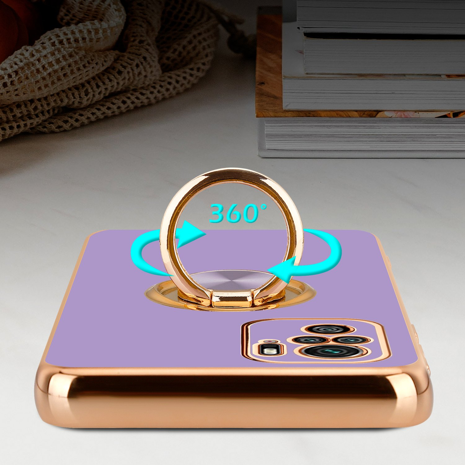 Telefono con custodia viola e anello dorato, con scrivania e libri sullo sfondo.