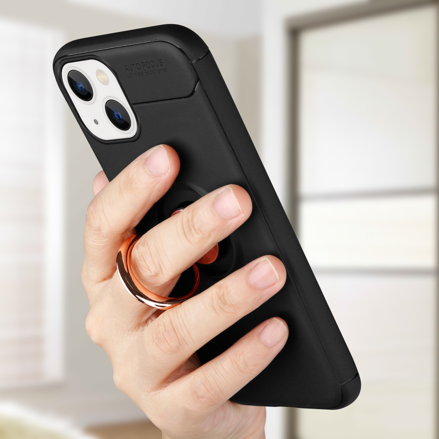 Hand hält ein schwarzes Telefon mit Ringhalter. Ringhalter ist bronzefarben.
