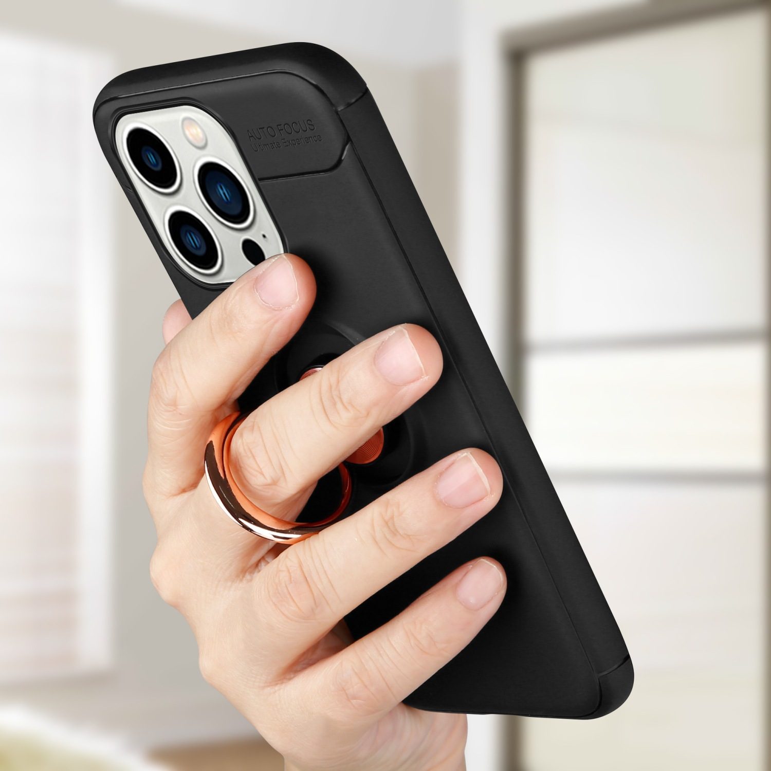 Hand hält ein schwarzes Telefon mit Ringhalter. Das Telefon ist in einer schwarzen Hülle.