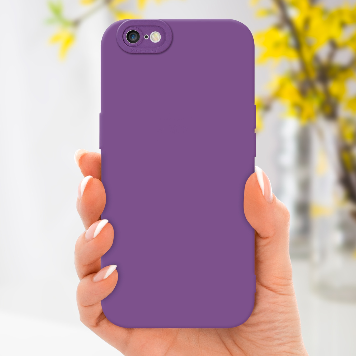 Mano che tiene una custodia viola con tripla fotocamera, con fiori gialli sfocati sullo sfondo.