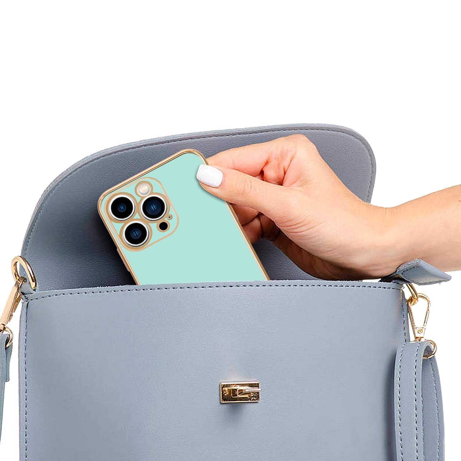 Eine Hand legt ein mintfarbenes Telefon in eine hellblaue Handtasche. Die Tasche ist geschlossen.