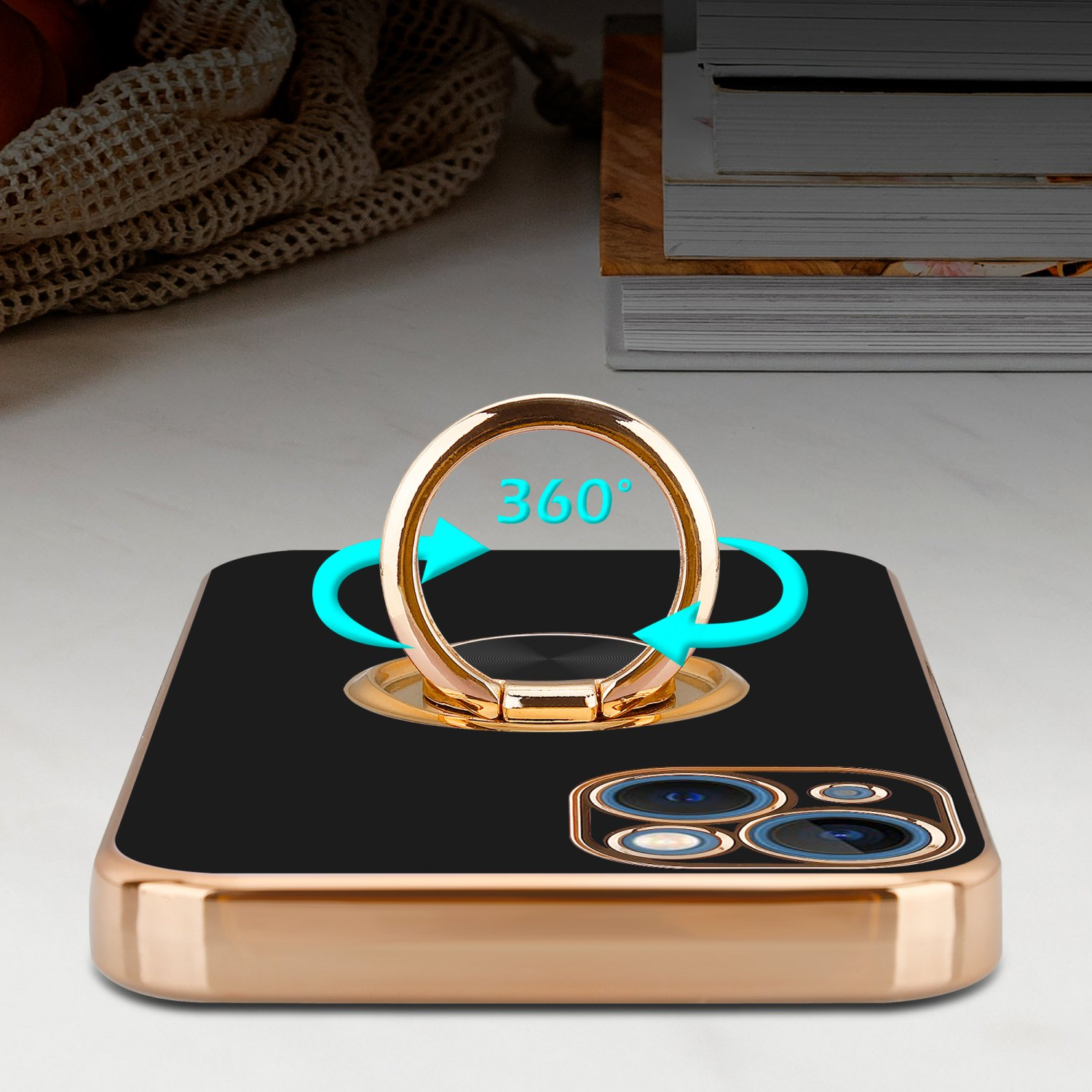 Schwarze Handyhülle mit goldenem Ringständer. Ring zeigt 360-Grad-Drehung. Hintergrund: Bücher.