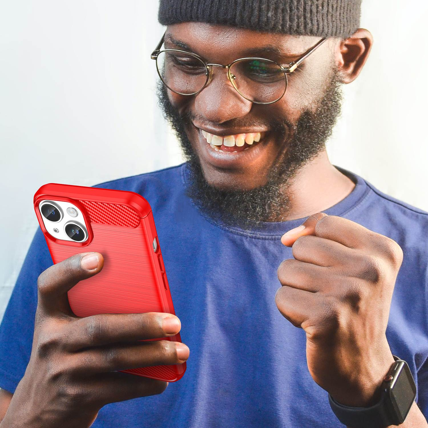 Ein Mann mit Brille lächelt, während er eine rote Handyhülle hält. Das Telefon hat eine Dreifachkamera.
