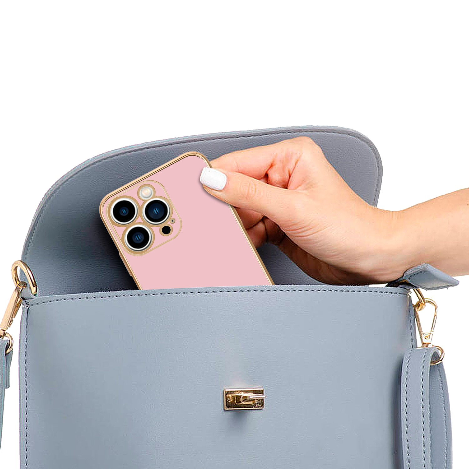 Ein rosa Telefon wird von einer Hand in eine blaue Handtasche gelegt. Die Tasche hat ein goldenes Schloss.