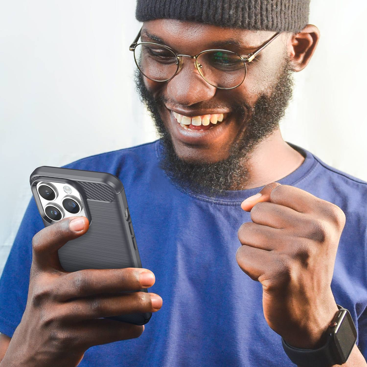 Lachender Mann hält ein Telefon mit schwarzer Hülle. Er trägt Brille und blaues Hemd.