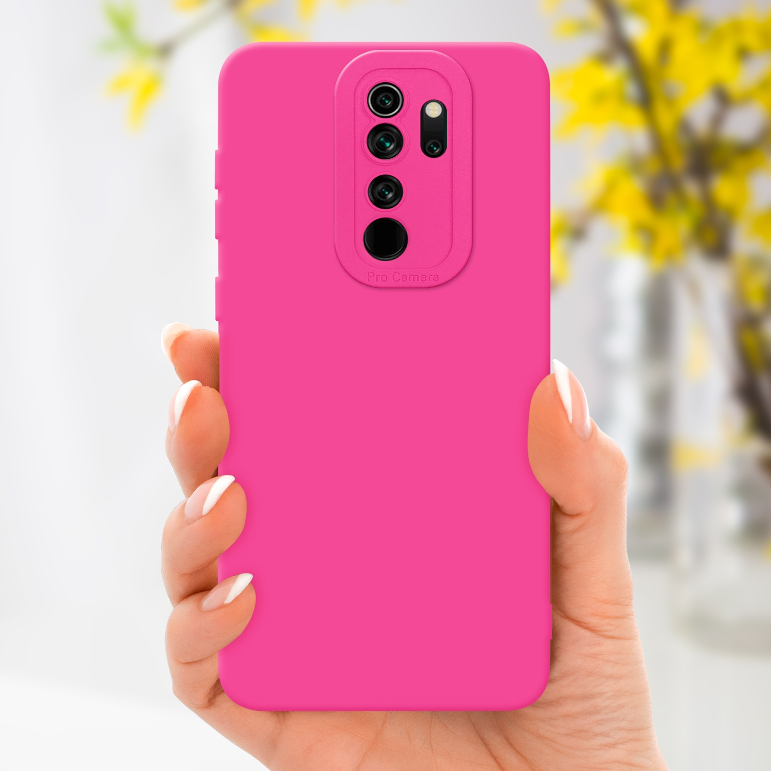 Una mano che tiene una custodia rosa. Fiori gialli sullo sfondo.