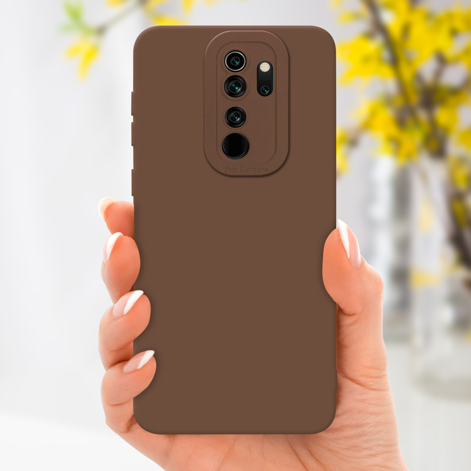 Custodia marrone per telefono tenuta da una persona, con un rialzo della fotocamera e testo Pro Camera, fiori gialli sullo sfondo.
