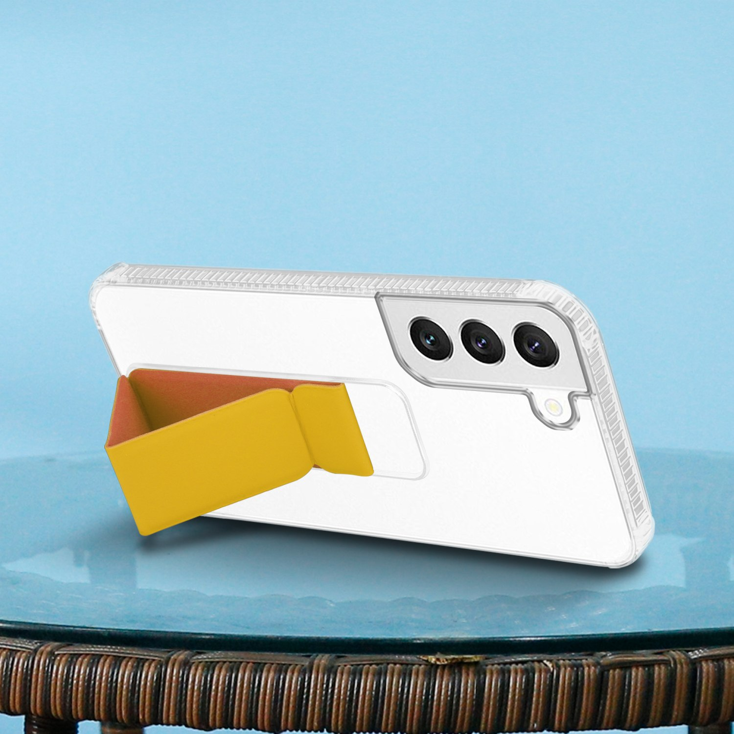 Ein Telefon mit einem gelben Ständer. Das Telefon hat eine transparente Hülle und befindet sich auf einer blauen Oberfläche.