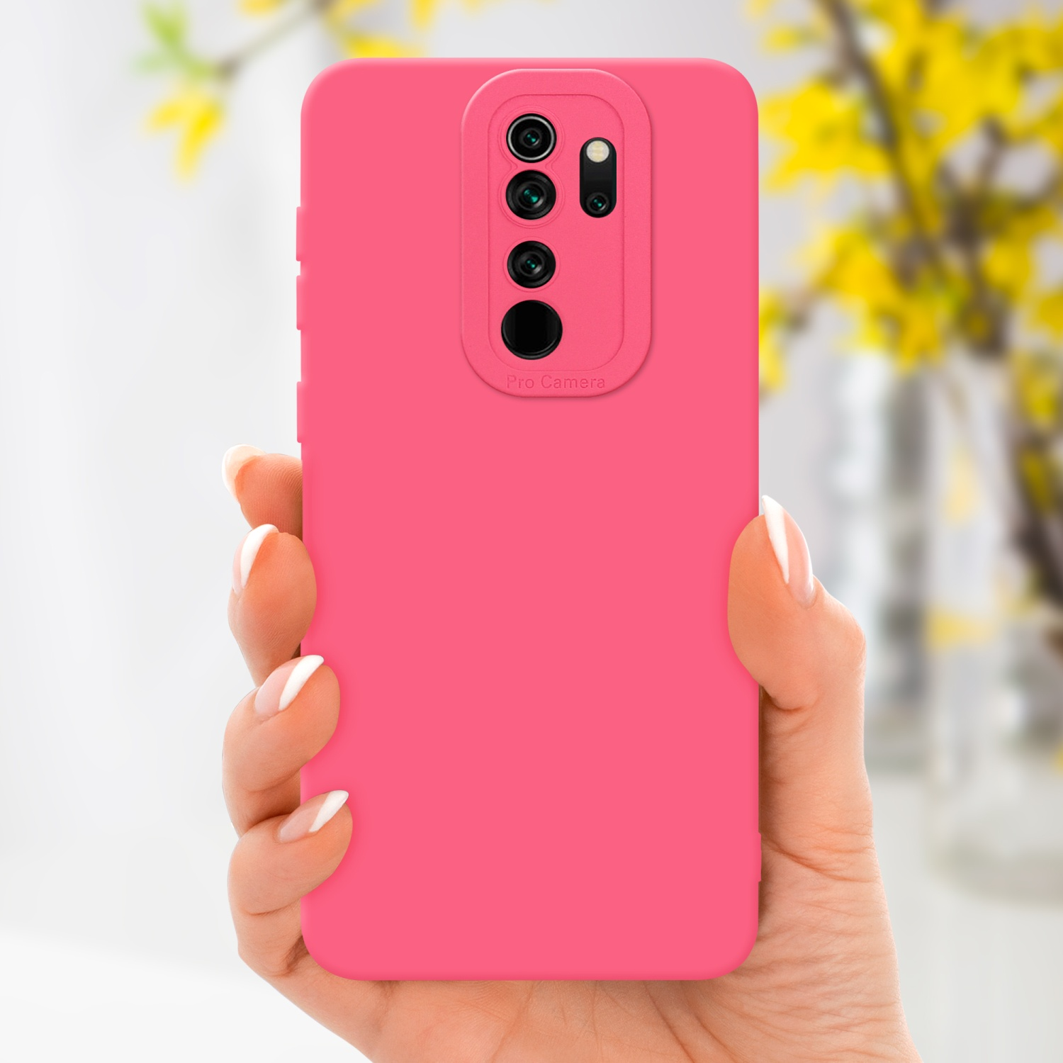 Mano che tiene una custodia rosa. Fiori gialli sfocati sullo sfondo.