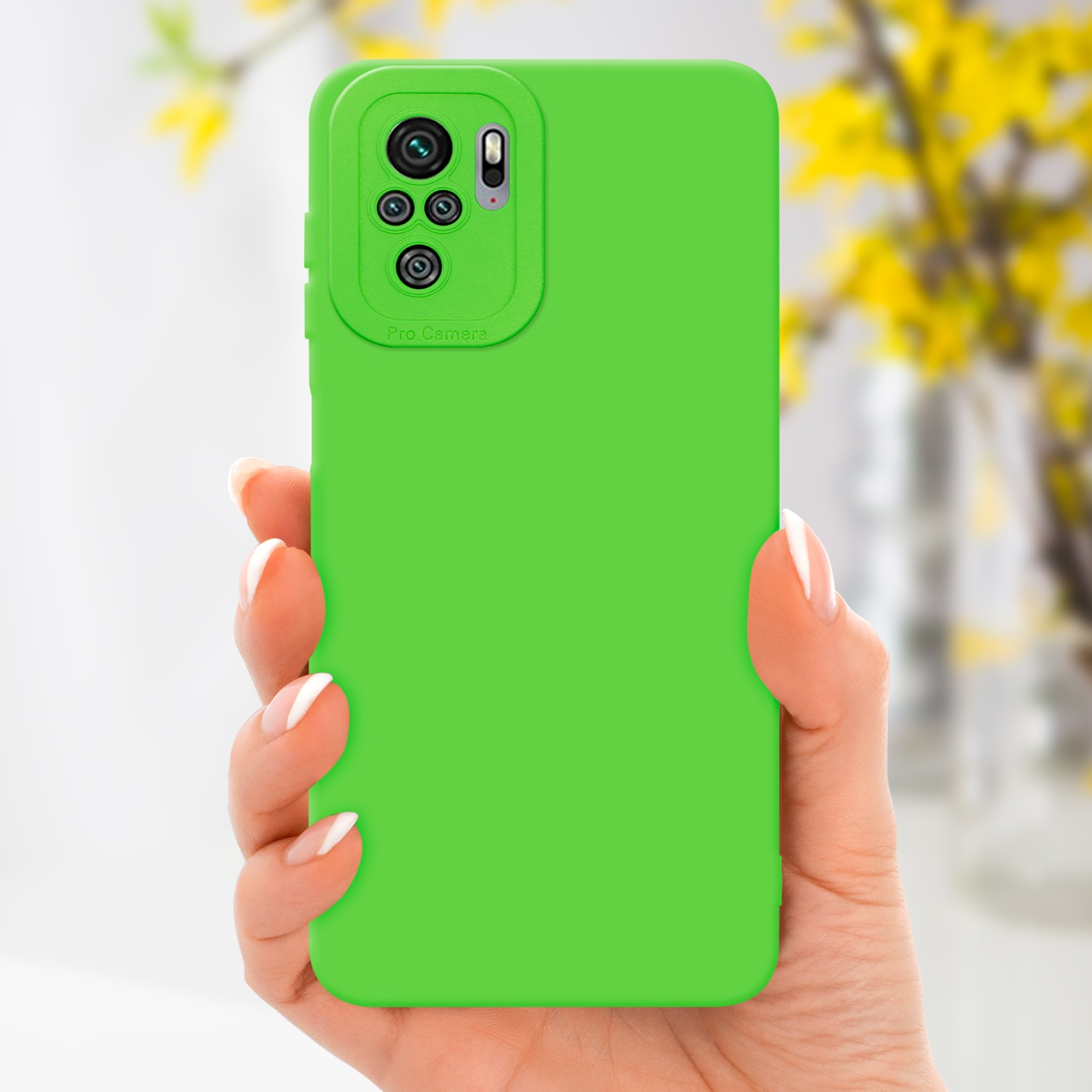 Una mano tiene un telefono viola con un supporto ad anello color oro. Fiori sullo sfondo.