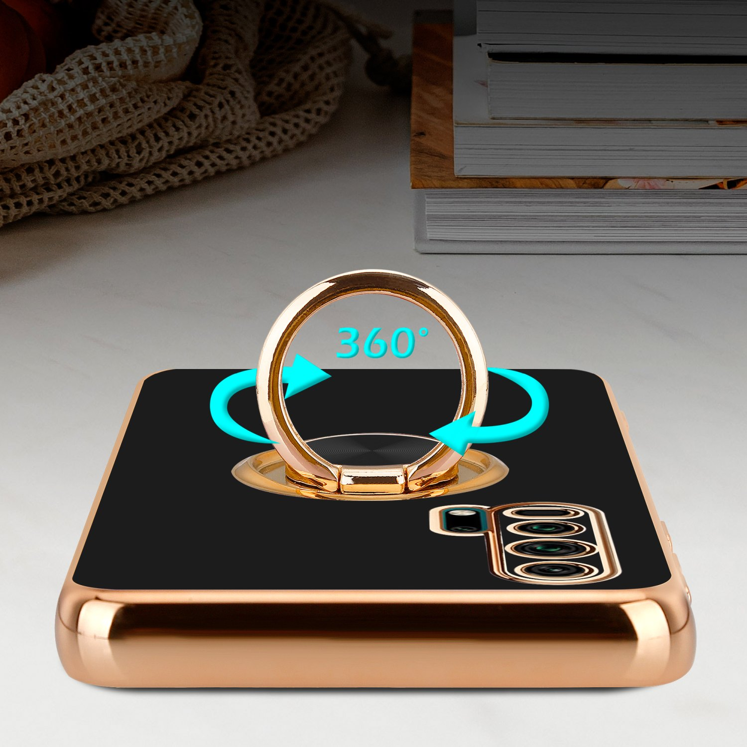 Schwarze Handyhülle mit goldenem Ringhalter, Pfeile zeigen 360° Drehung, auf einer Oberfläche.