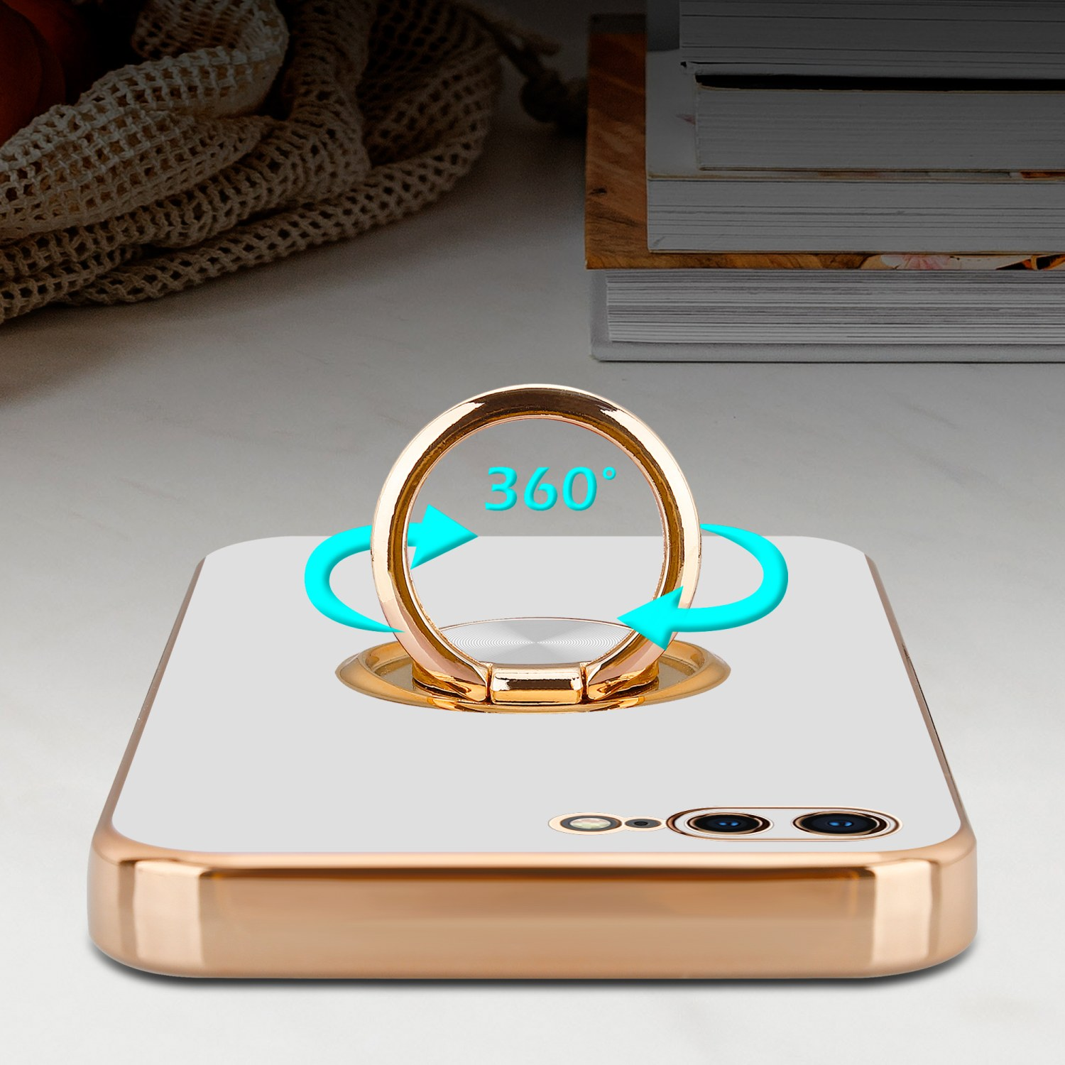 Goldene Handyhülle mit Ringständer. Der Ring zeigt eine 360-Grad-Drehung. Bücher sind im Hintergrund.