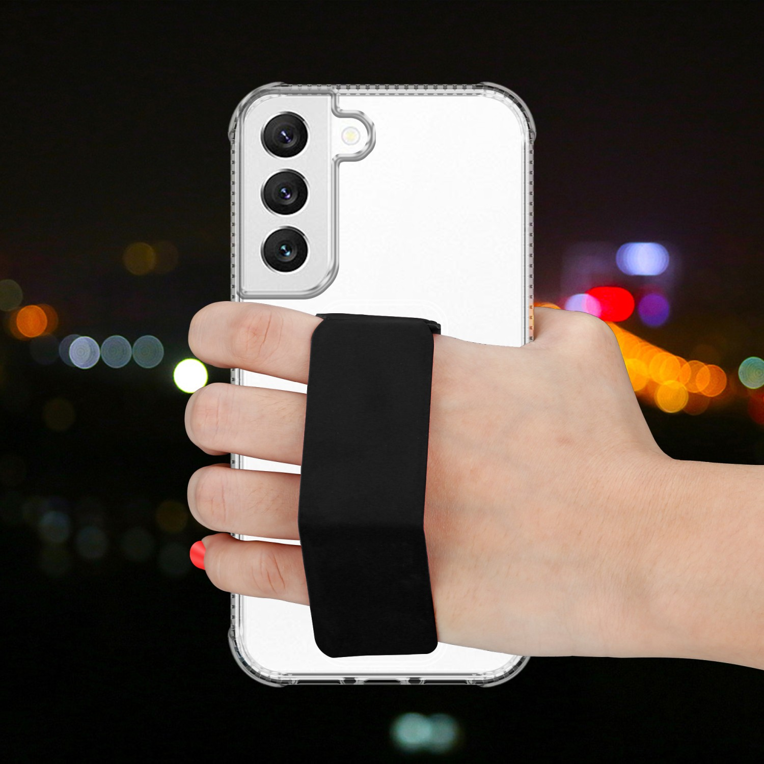 Eine Hand, die ein klares Telefon mit einem schwarzen Riemen hält. Der Hintergrund hat Bokeh-Lichter.