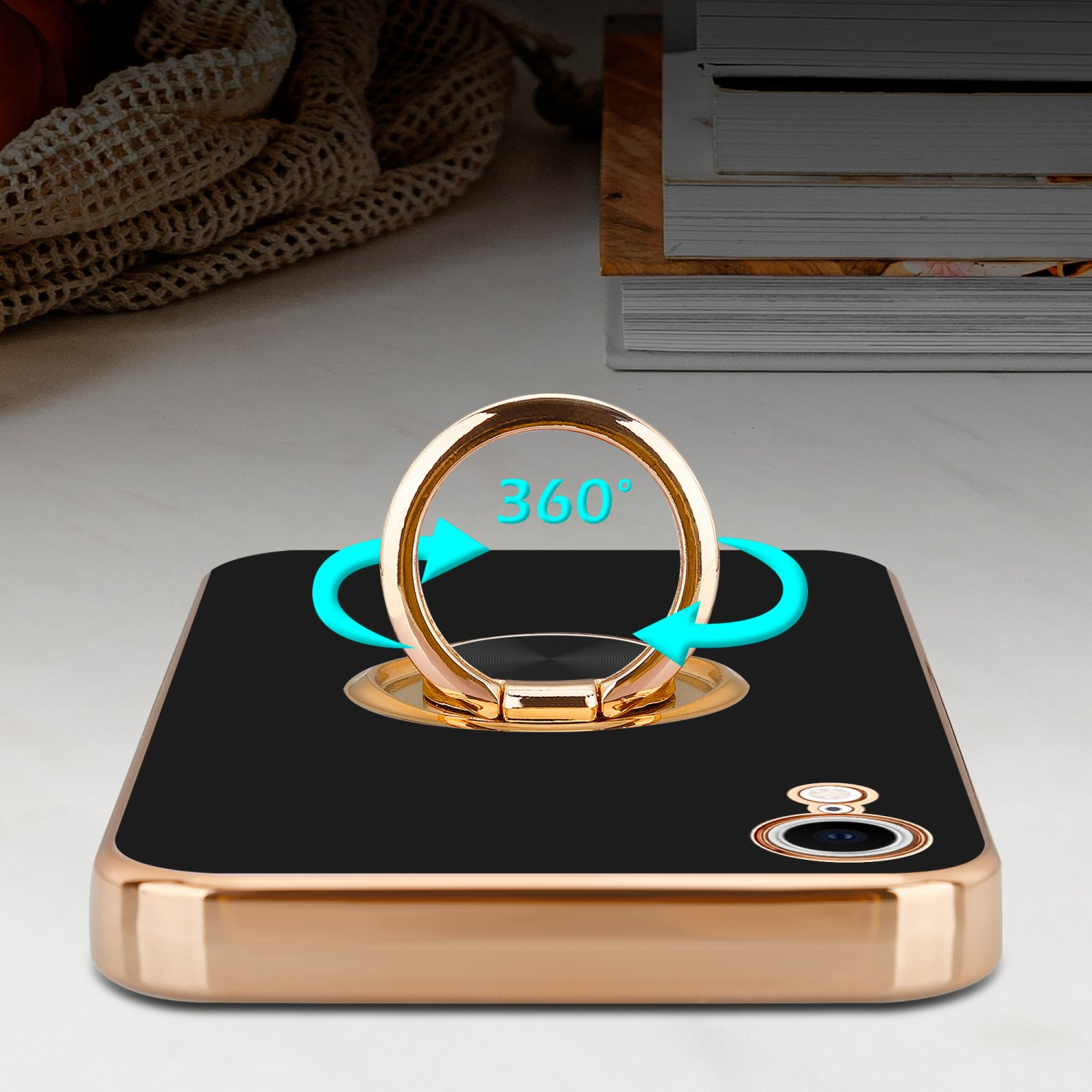 Schwarze Handyhülle mit goldenem Ring, Pfeile zeigen 360° Drehung, Bücher im Hintergrund.
